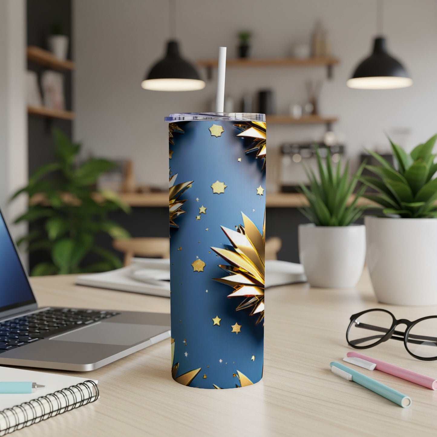 Blue tumbler with gold starbursts and a white straw on a desk.