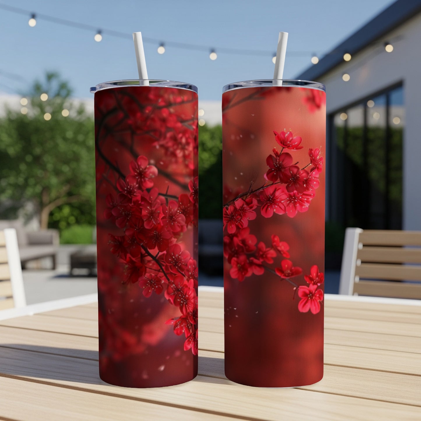 Two red cherry blossom tumblers with straws on a table outdoors.