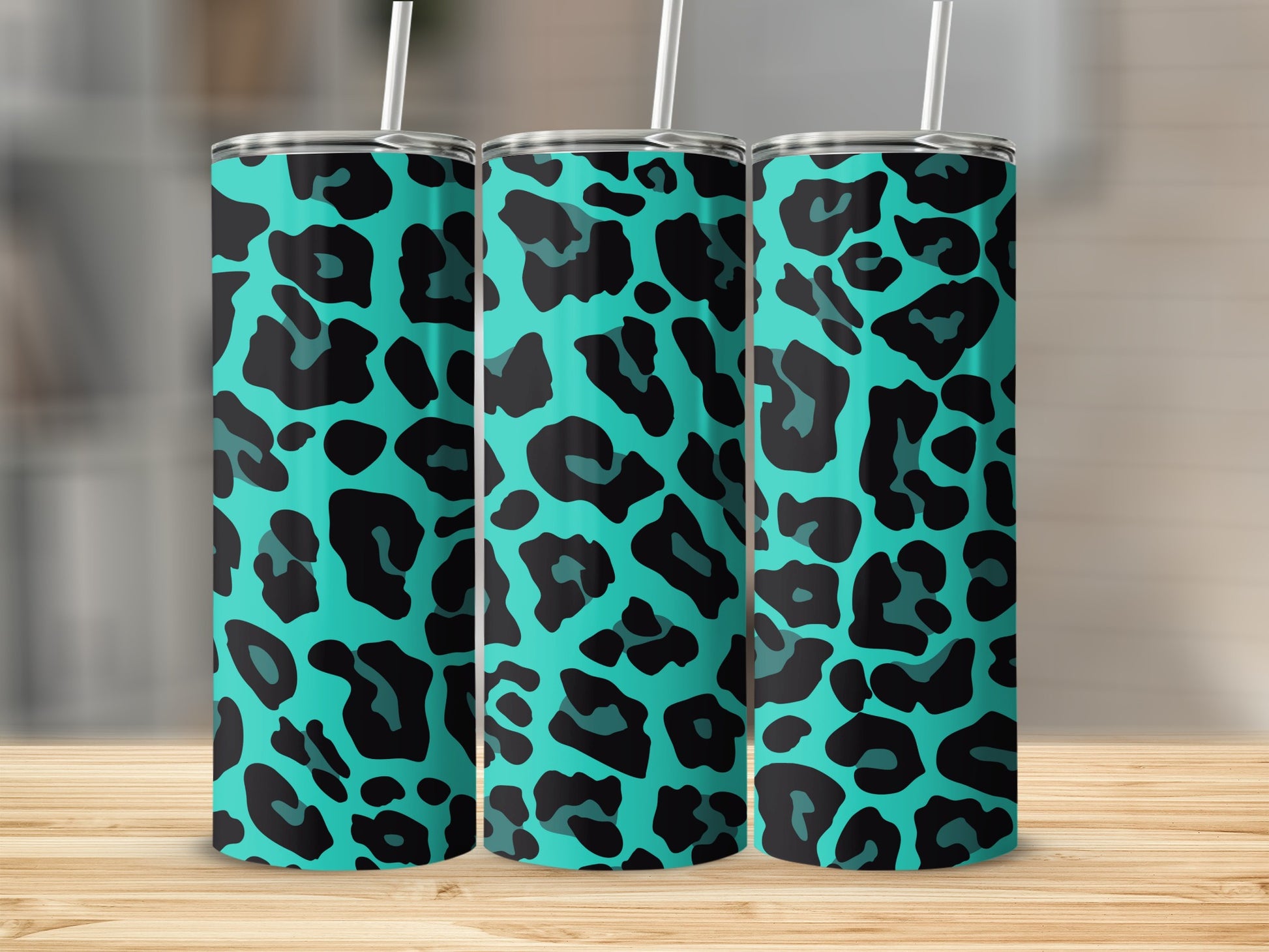 Three aqua tumblers with a black leopard print pattern stand on a wooden surface.