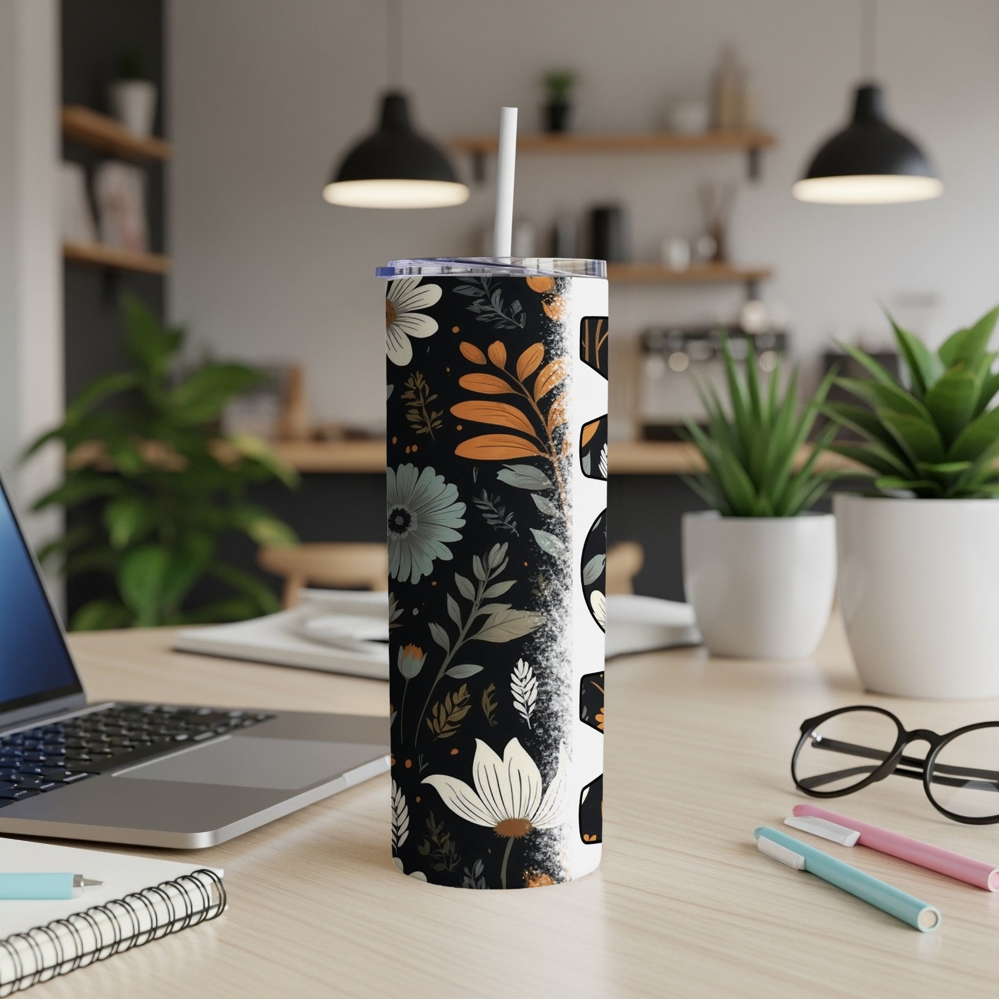 Floral and skull pattern tumbler with a straw on a wooden desk.