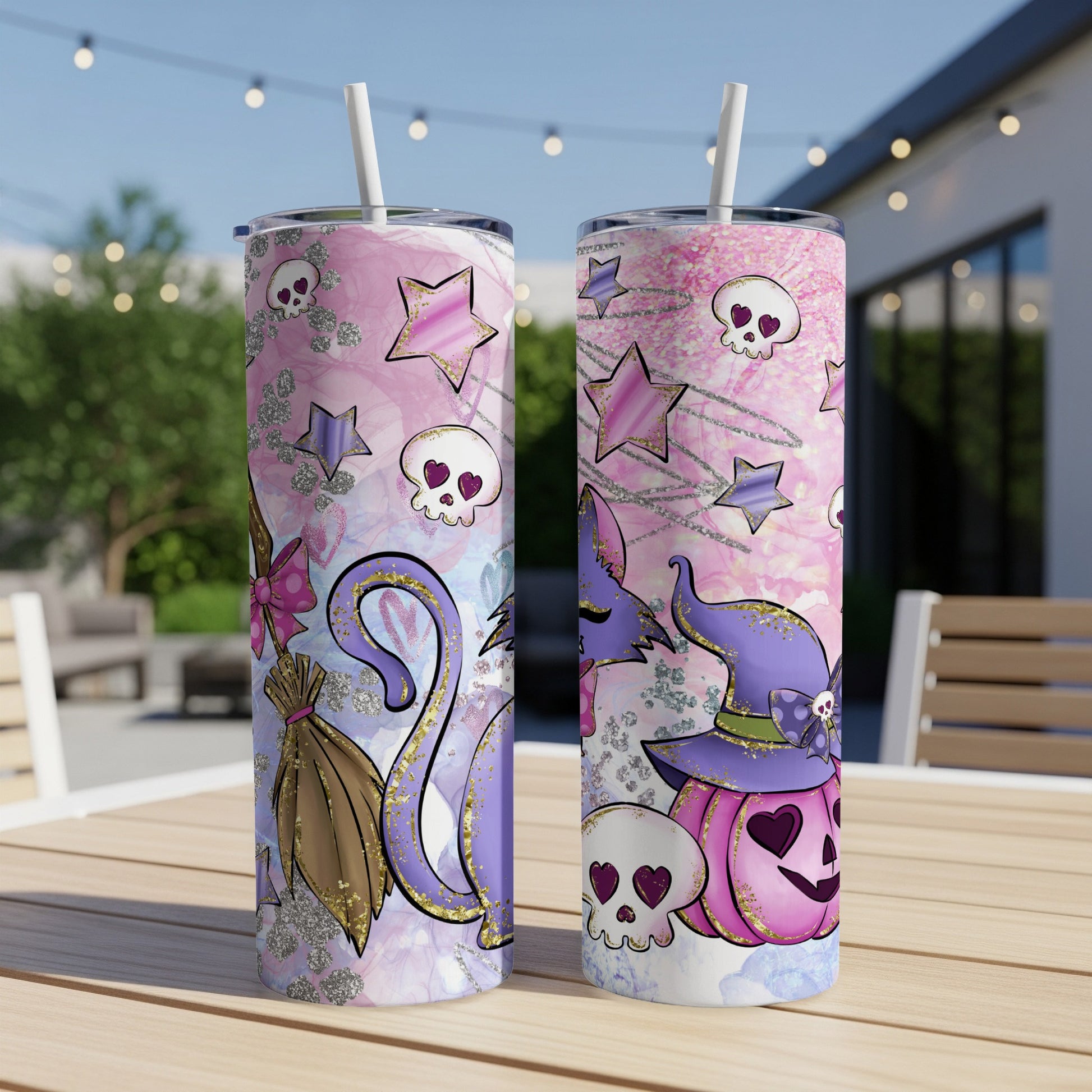 Two Halloween-themed tumblers with cats, pumpkins, and skulls on a patio table.