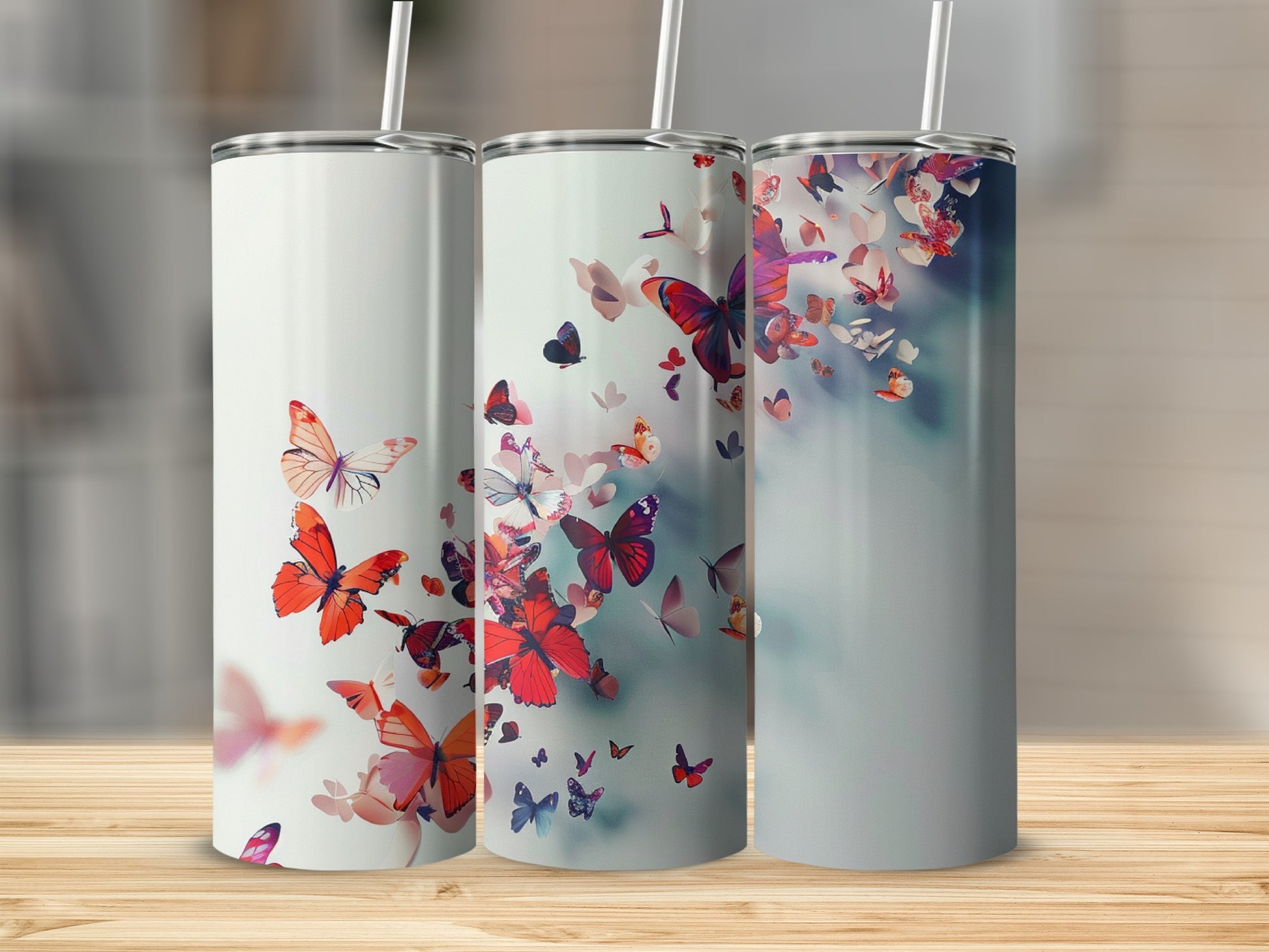 Three tumblers with red and pink butterflies on a wooden surface.