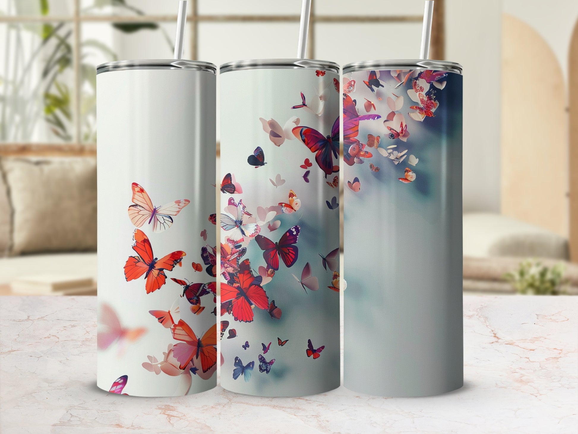 Three tumblers with butterfly designs in shades of pink and red.