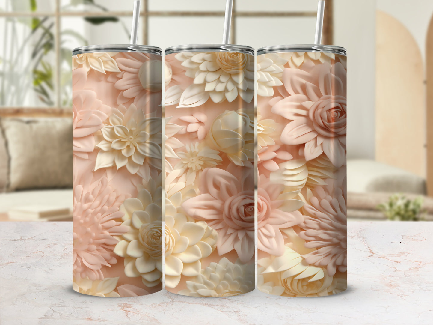 Three floral patterned tumblers with straws on a marble surface.