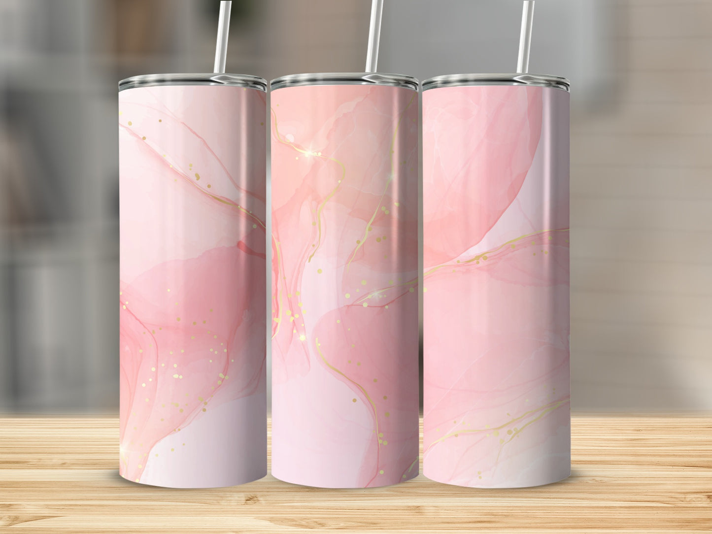 Three pink marble-patterned tumblers with gold accents stand on a wooden surface.