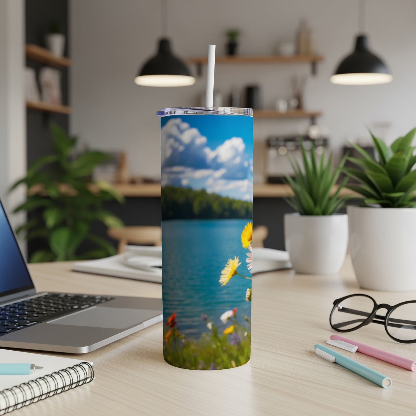 Tall tumbler with a lake and wildflower scene, resting on a desk.