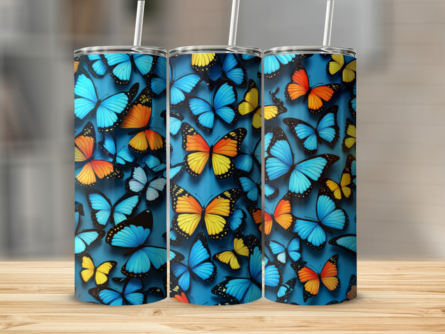 Three tumblers covered in colorful butterflies on a wooden surface.