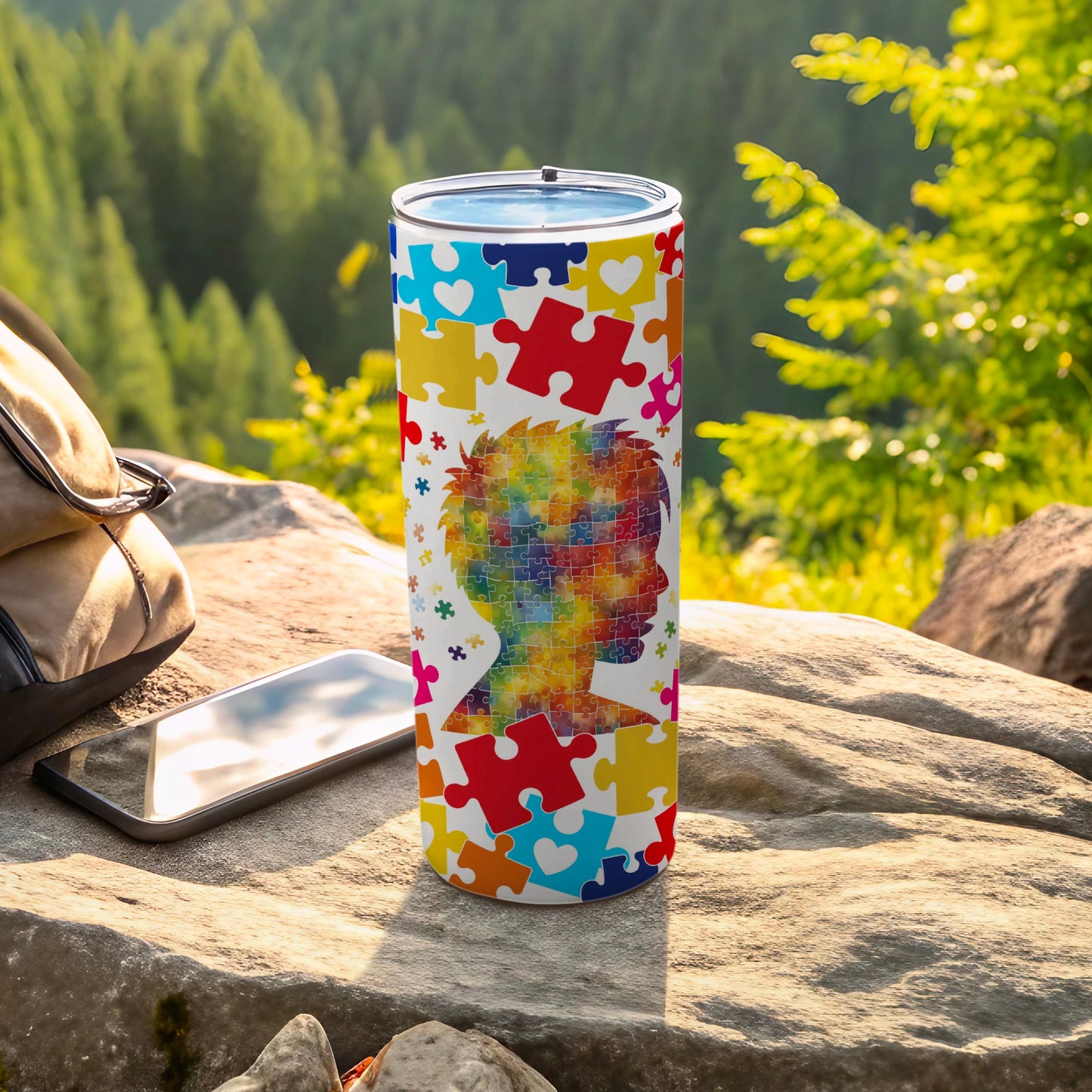 Tumbler with colorful puzzle pieces forming a head silhouette against a natural background.