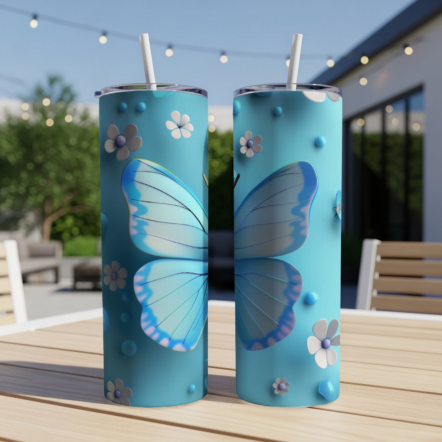 Two blue tumblers with butterfly and floral designs on a table.
