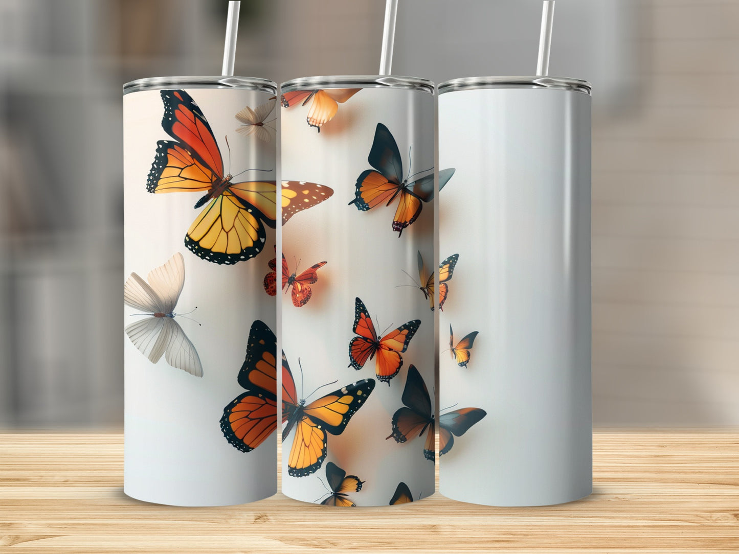 Three tumblers with butterfly designs on a wooden surface.
