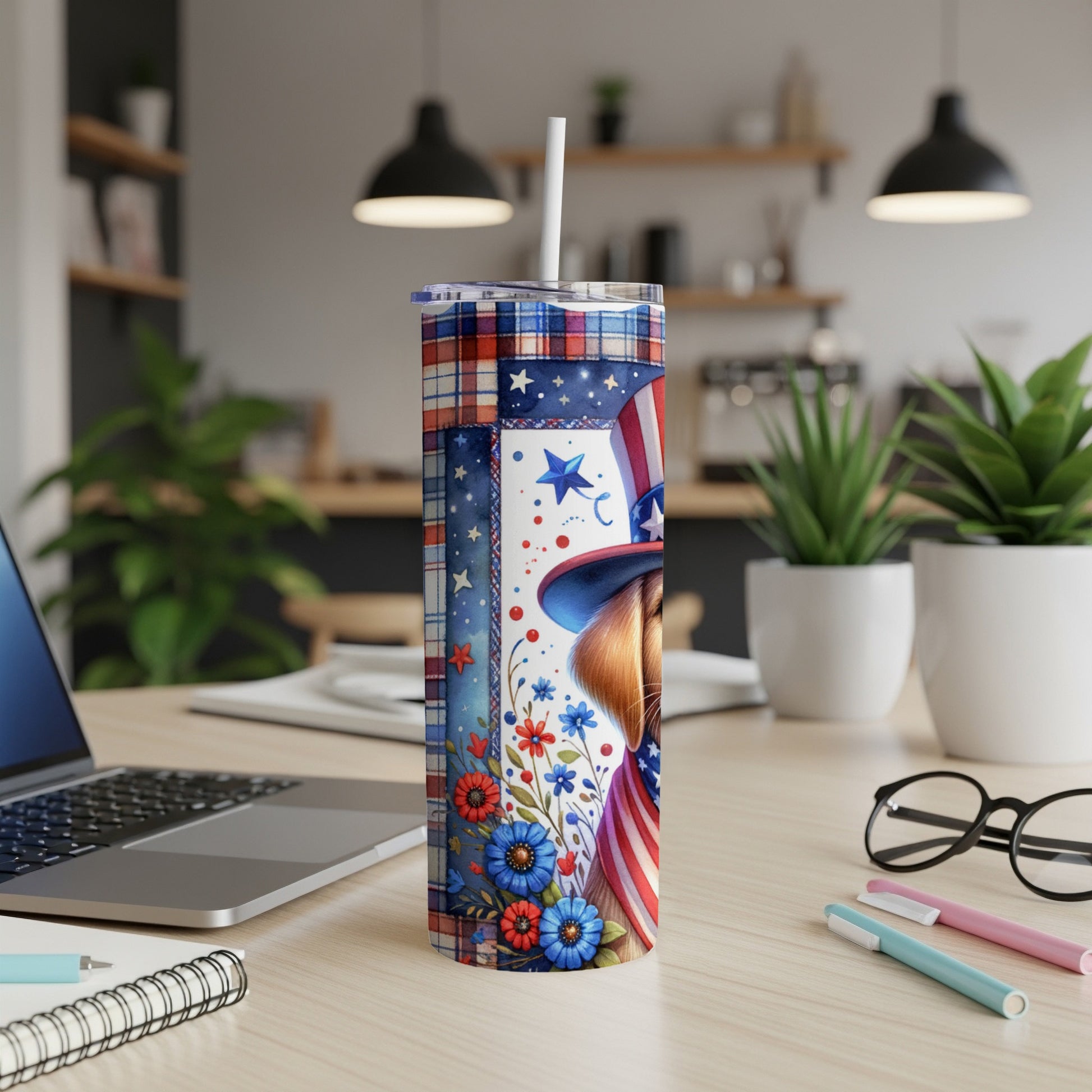 Patriotic tumbler with stars, stripes, and floral design on a desk.