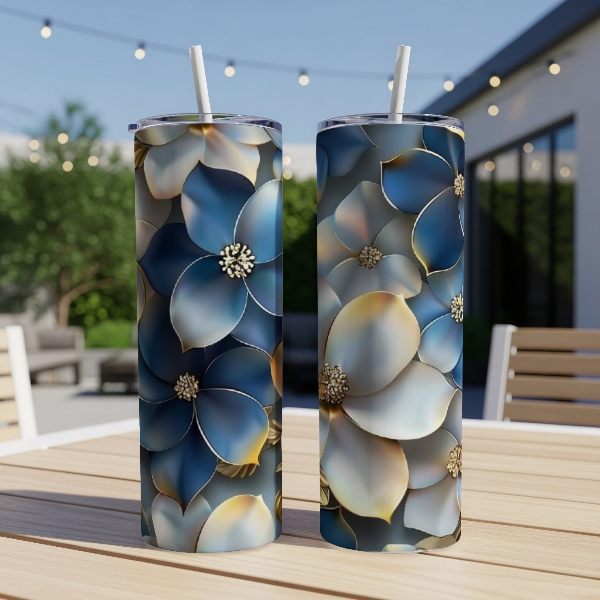 Two tall tumblers with blue and gold floral design sit on a table outdoors.