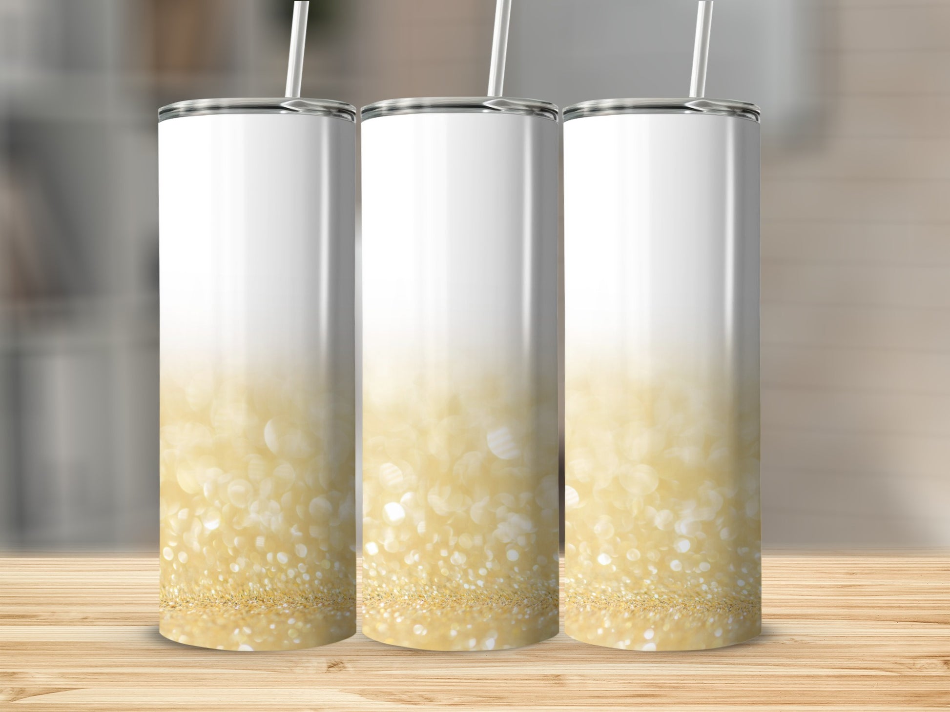 Three white tumblers with gold glitter ombre design and straws.