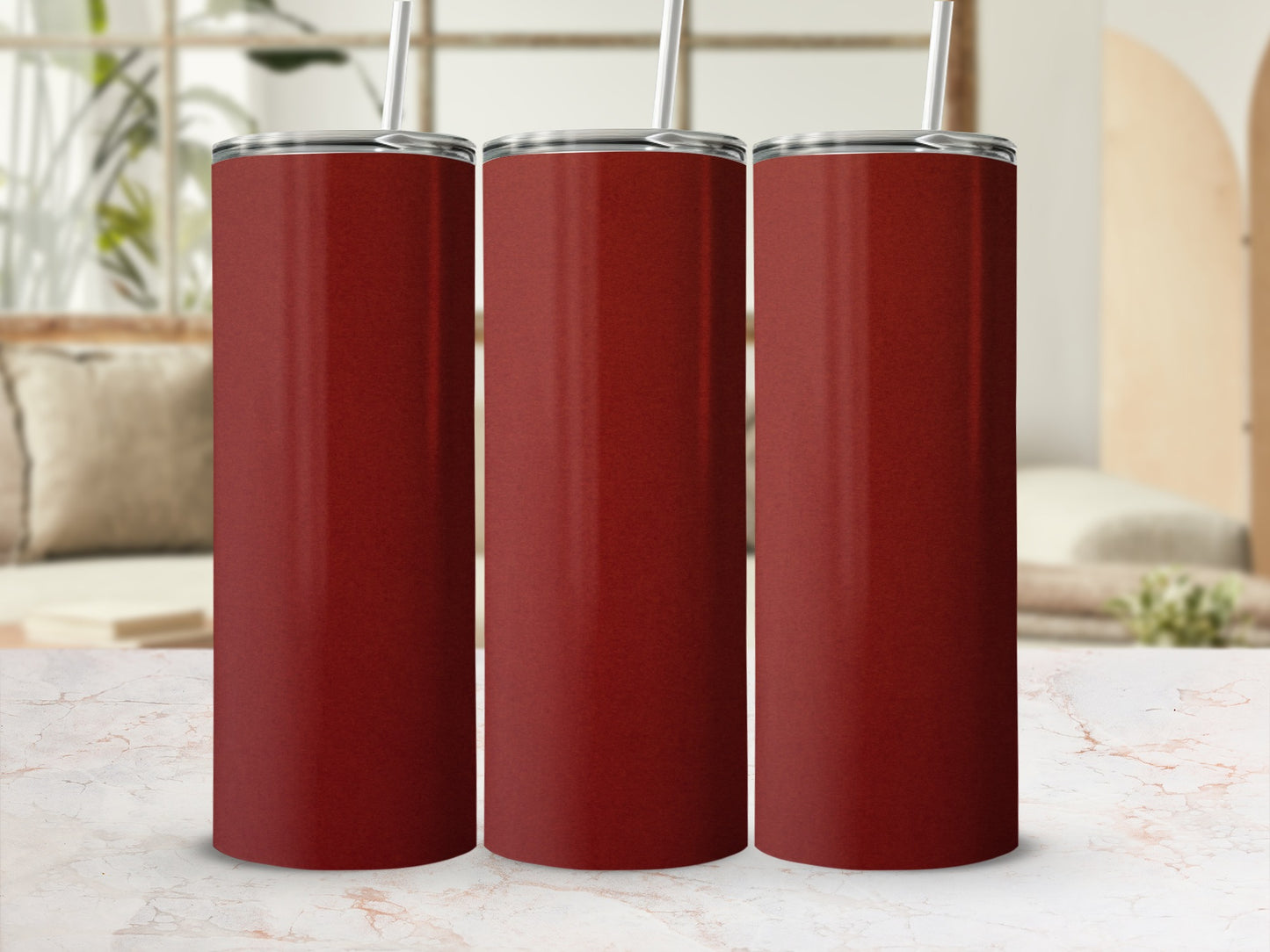 Three tall, plain red tumblers with straws on a marble surface.