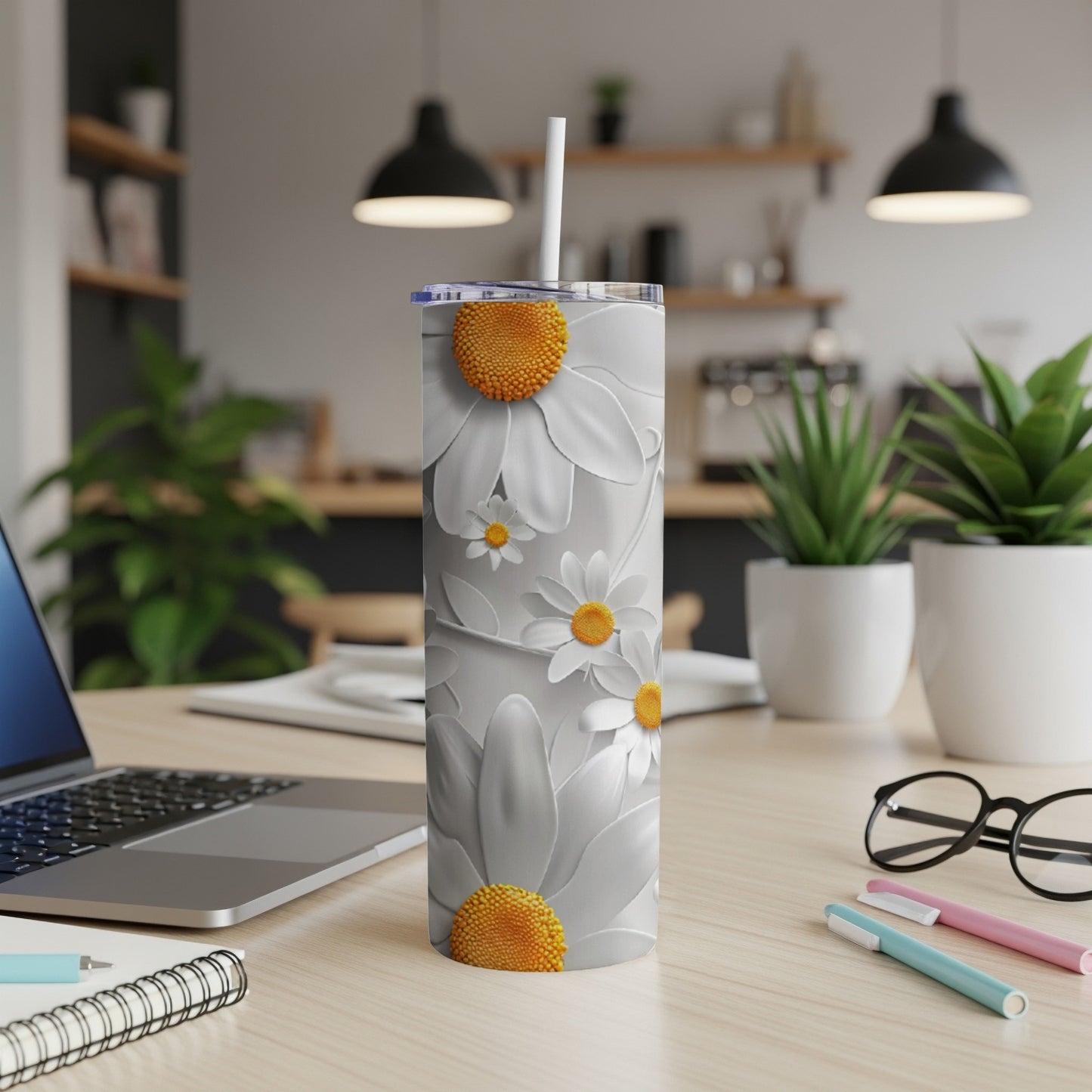 White floral tumbler with orange centers on a desk with a laptop.
