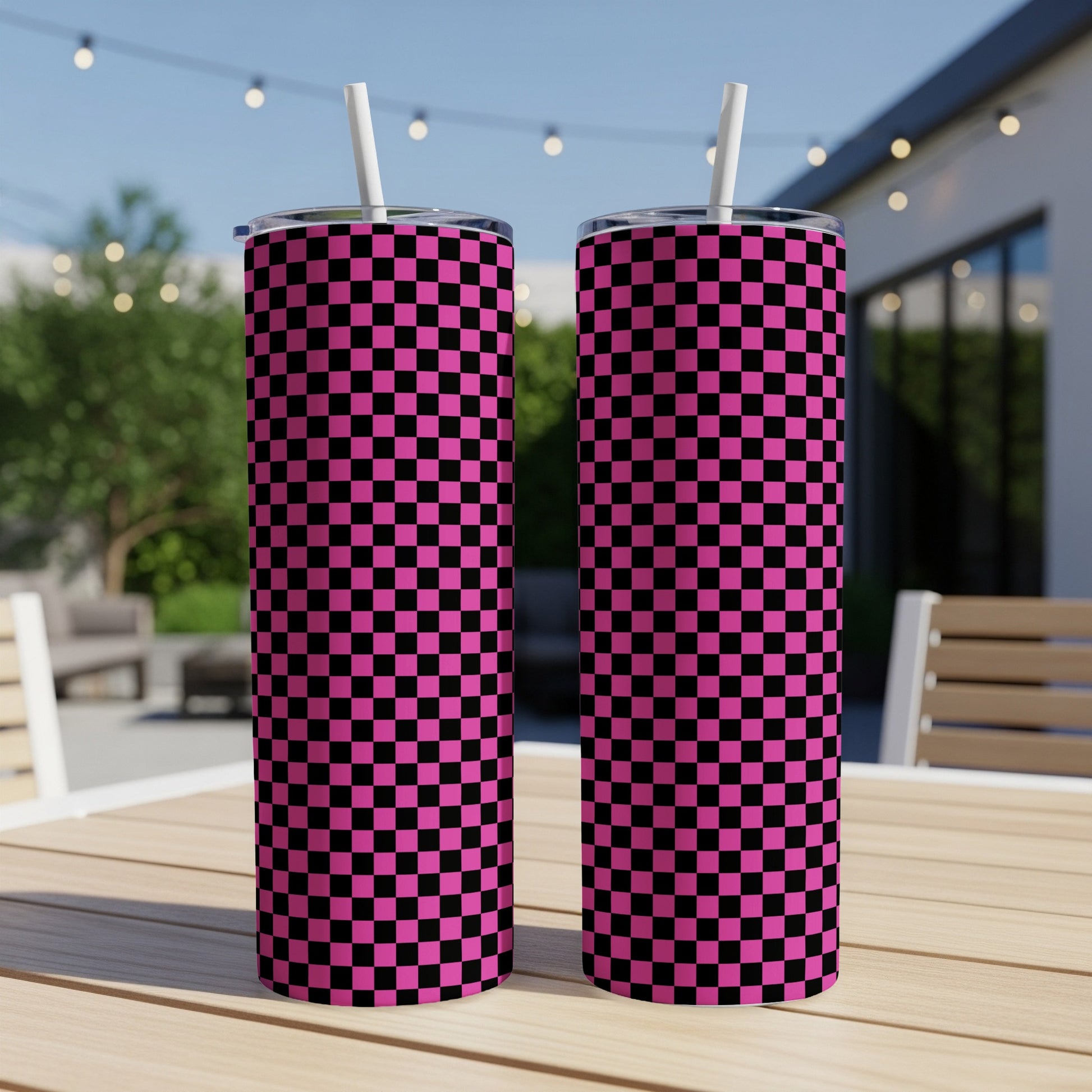 Two pink and black checkered tumblers with straws on a table.