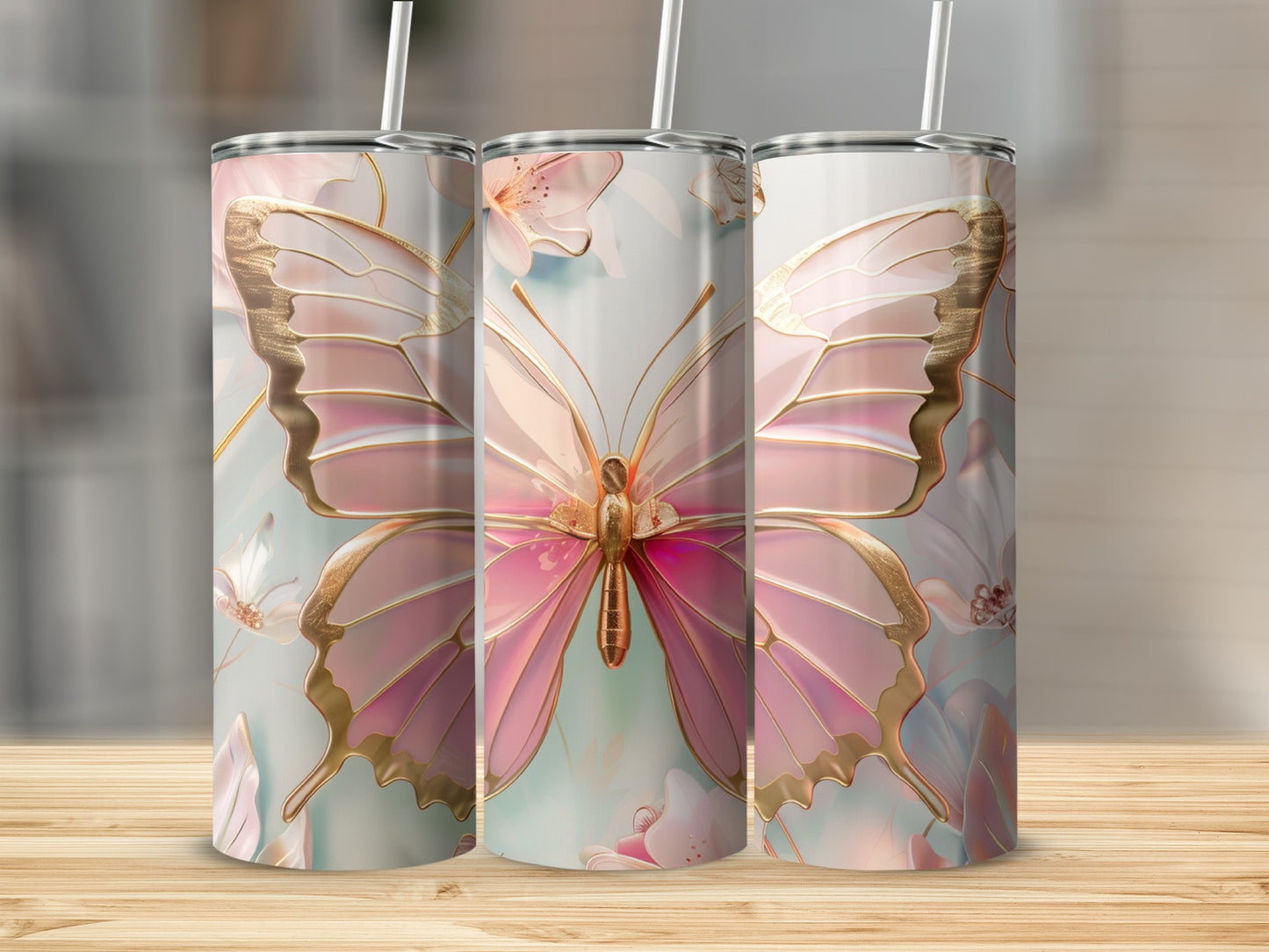 Pink butterfly design on three tumblers with straws on a wooden surface.