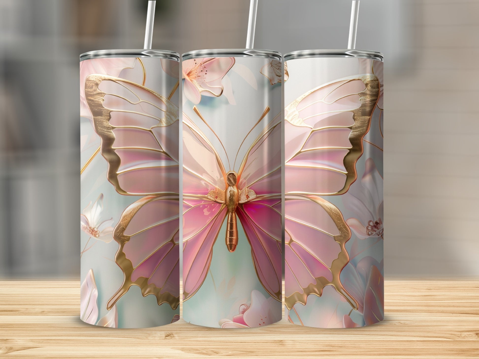 Pink butterfly design on three tumblers with straws on a wooden surface.