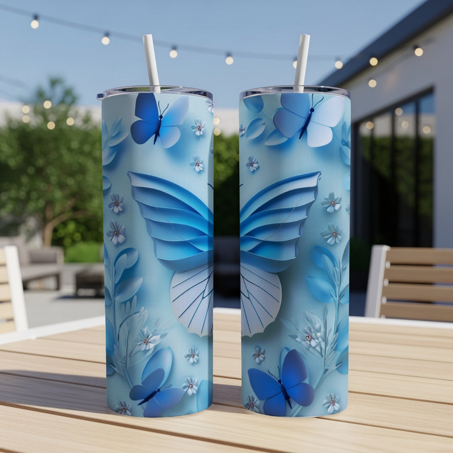 Two blue butterfly pattern tumblers with straws on a wooden table.