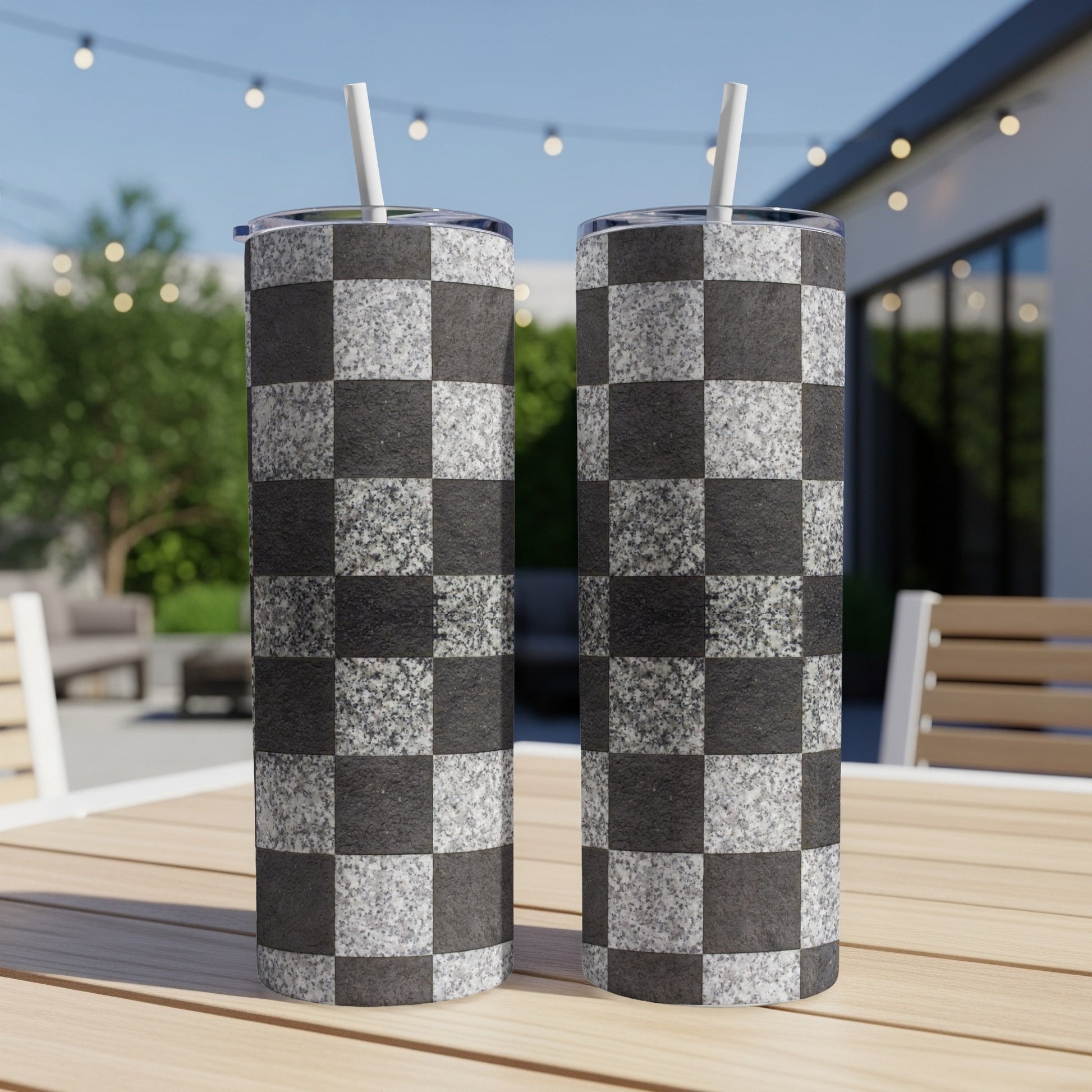 Two tall tumblers with a black and white checkerboard pattern, with straws.