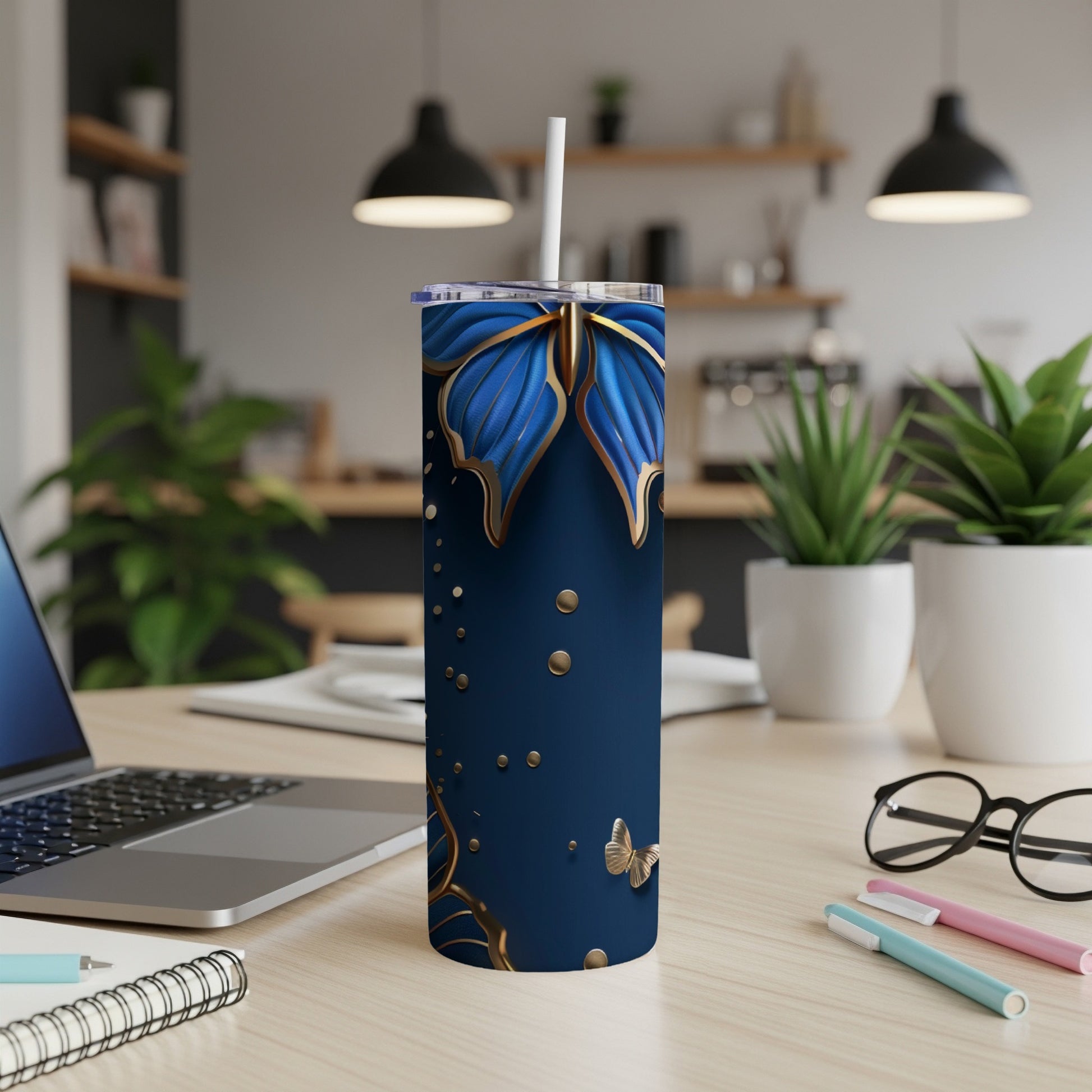 Blue tumbler with gold butterflies and gold accents, on a desk.