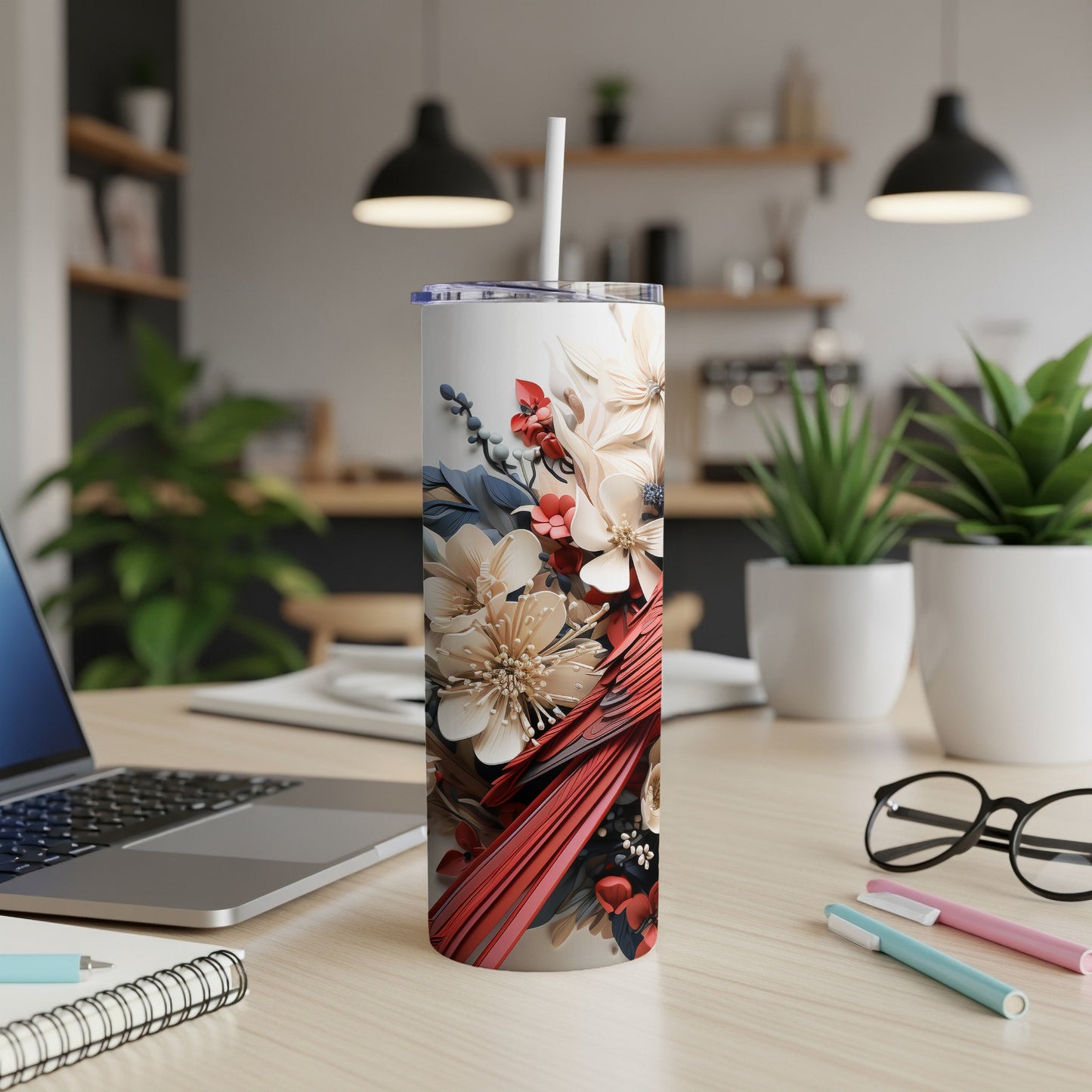 White floral tumbler with red cardinal on a desk with a laptop and pens.