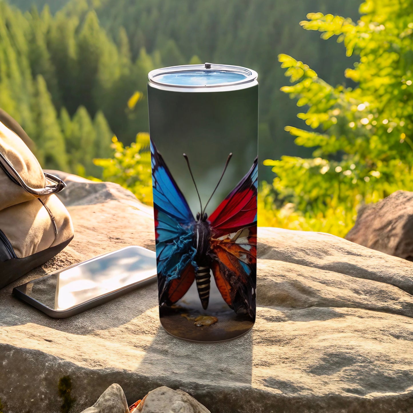 Tumbler with a butterfly graphic, alongside a backpack and phone.