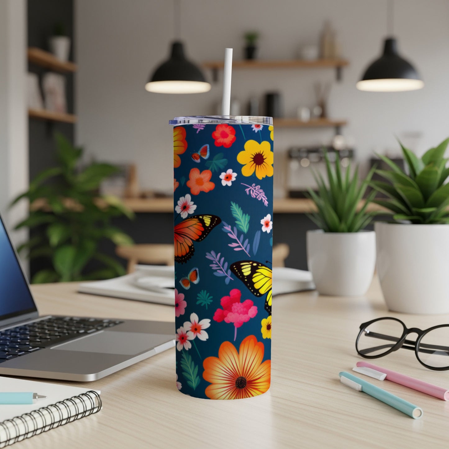 Tumbler with butterflies and floral pattern, a straw rests inside.