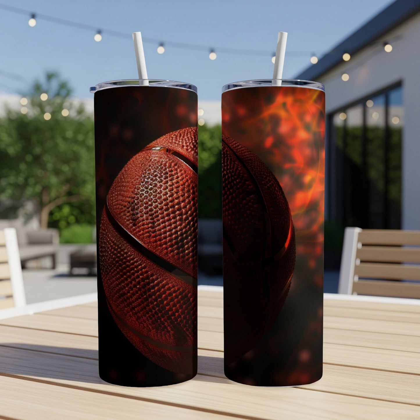 Two basketball tumblers with straws sit on a wooden table with a fiery background.