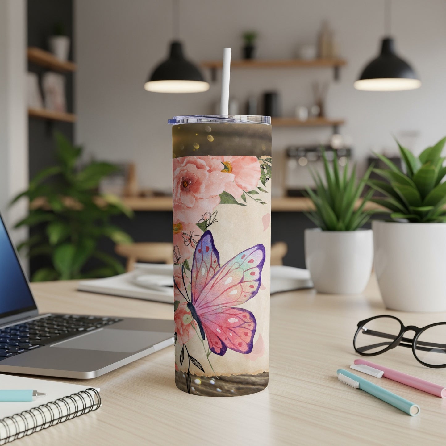 Tumbler with butterfly and floral design on wooden surface.