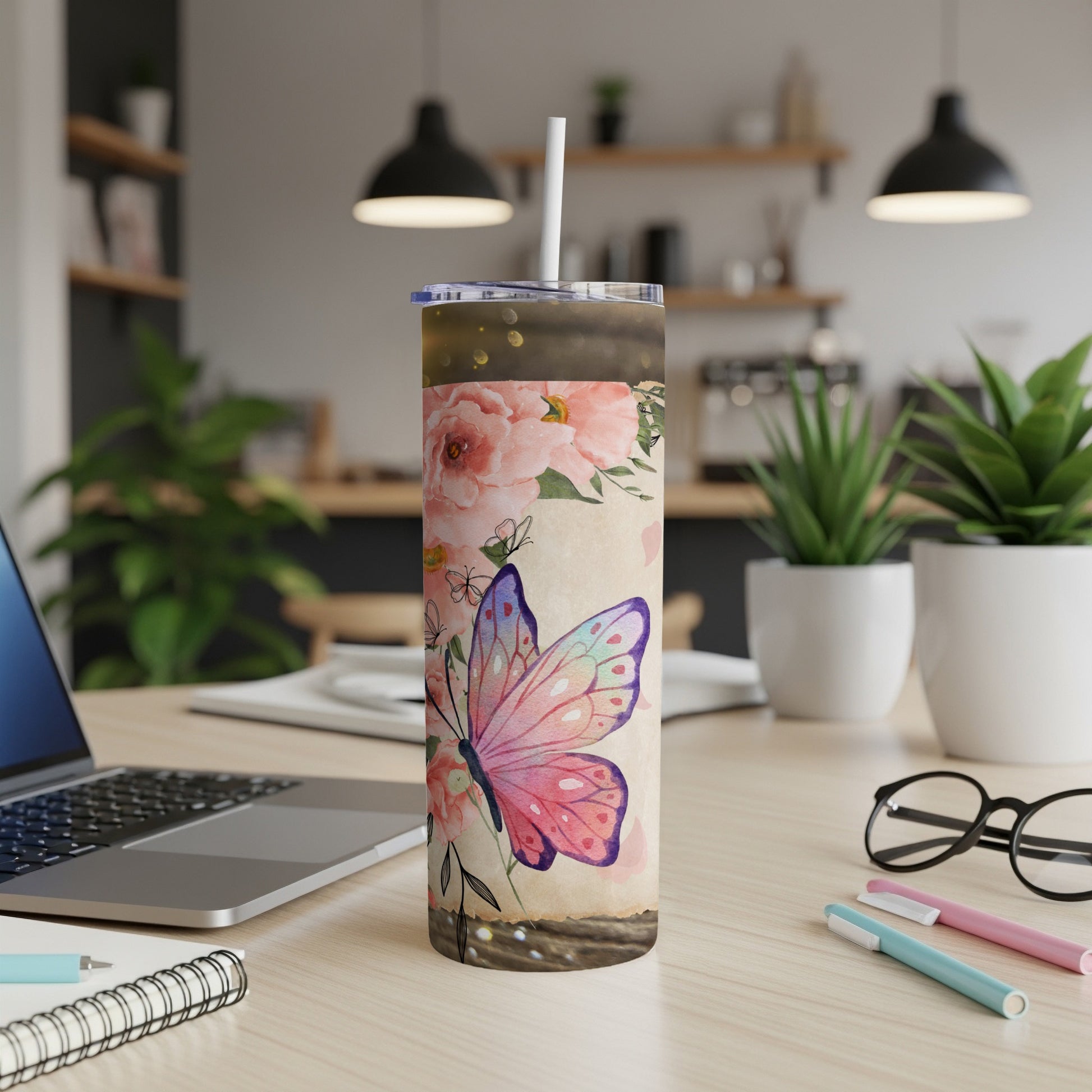 Tumbler with butterfly and floral design on wooden surface.