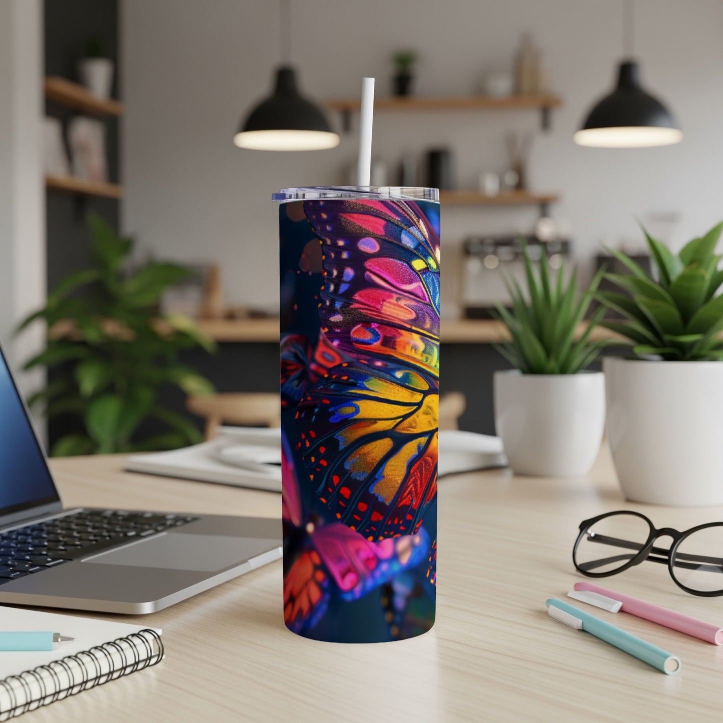 Tumbler with a vibrant butterfly wing design and a straw.
