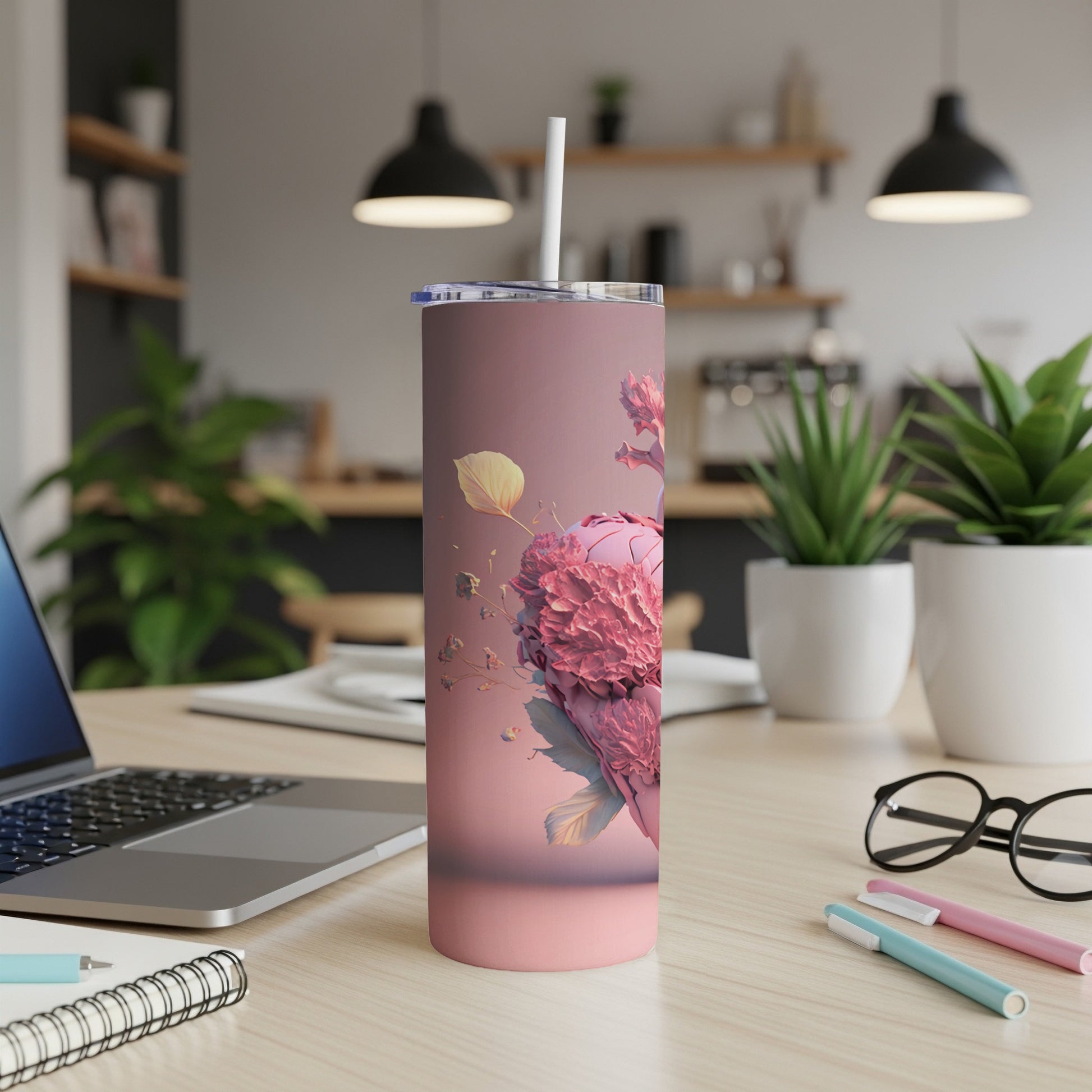 Pink tumbler with floral heart design and straw on a desk.