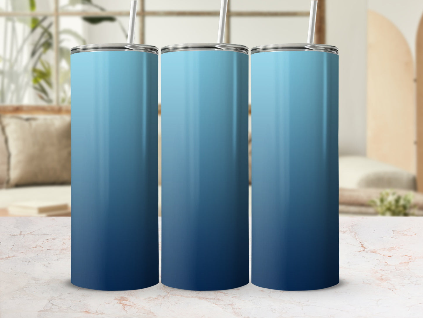 Three blue gradient tumblers with straws on a marble surface.