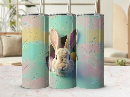Easter bunny peeking from pastel cracked egg on two tumblers.