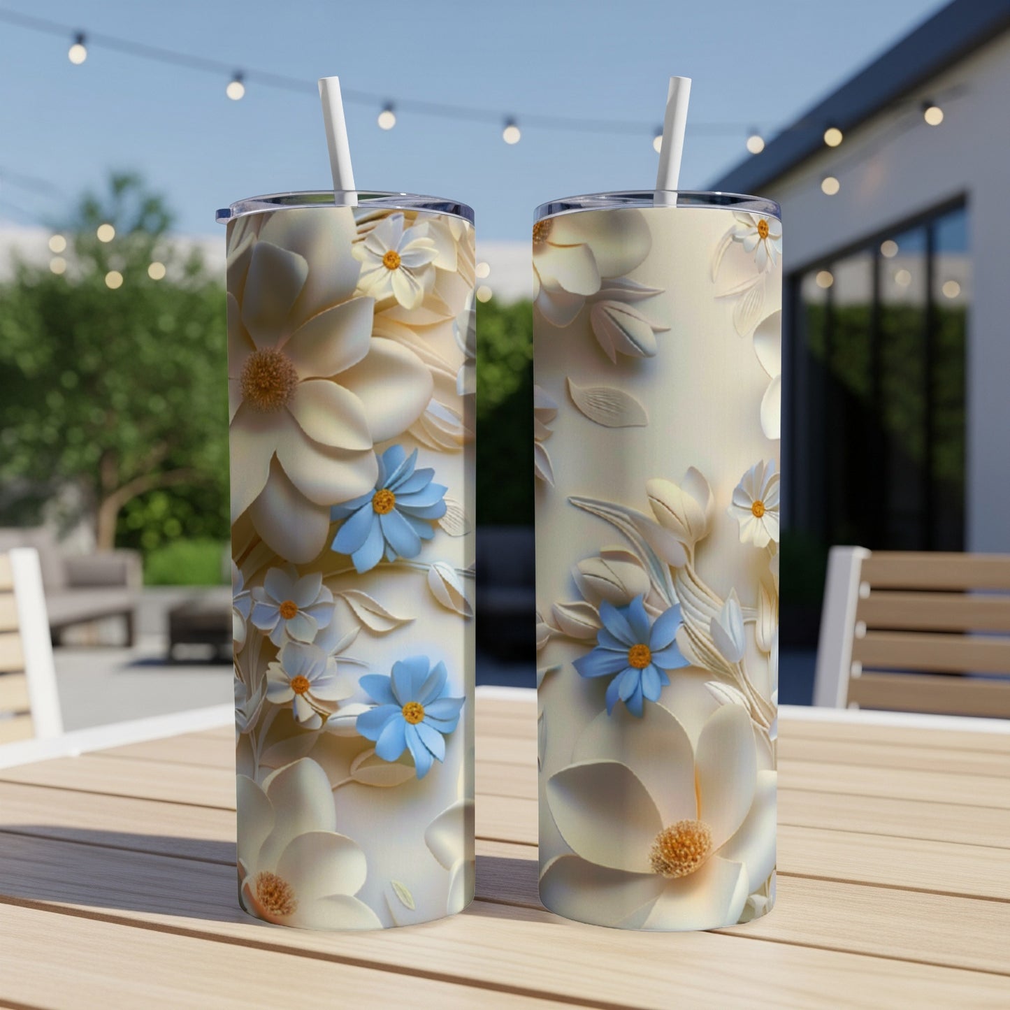 Two tall, slender tumblers with cream and blue floral designs sit on a wooden table.