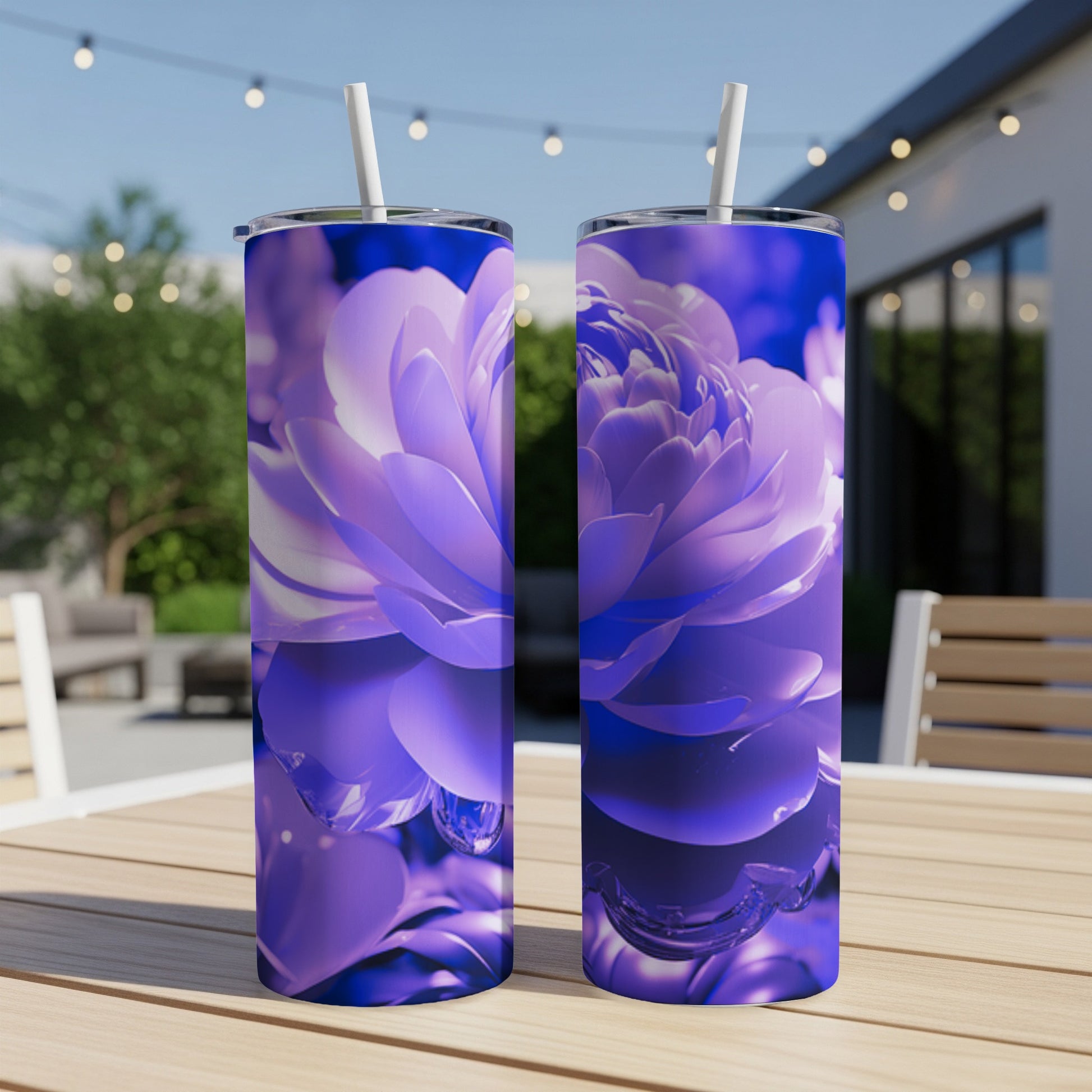 Two purple floral tumblers with straws on a table outdoors.