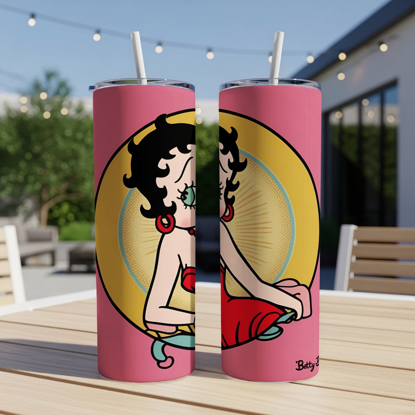 Betty Boop character illustration on a pink tumbler with straw, outdoors.