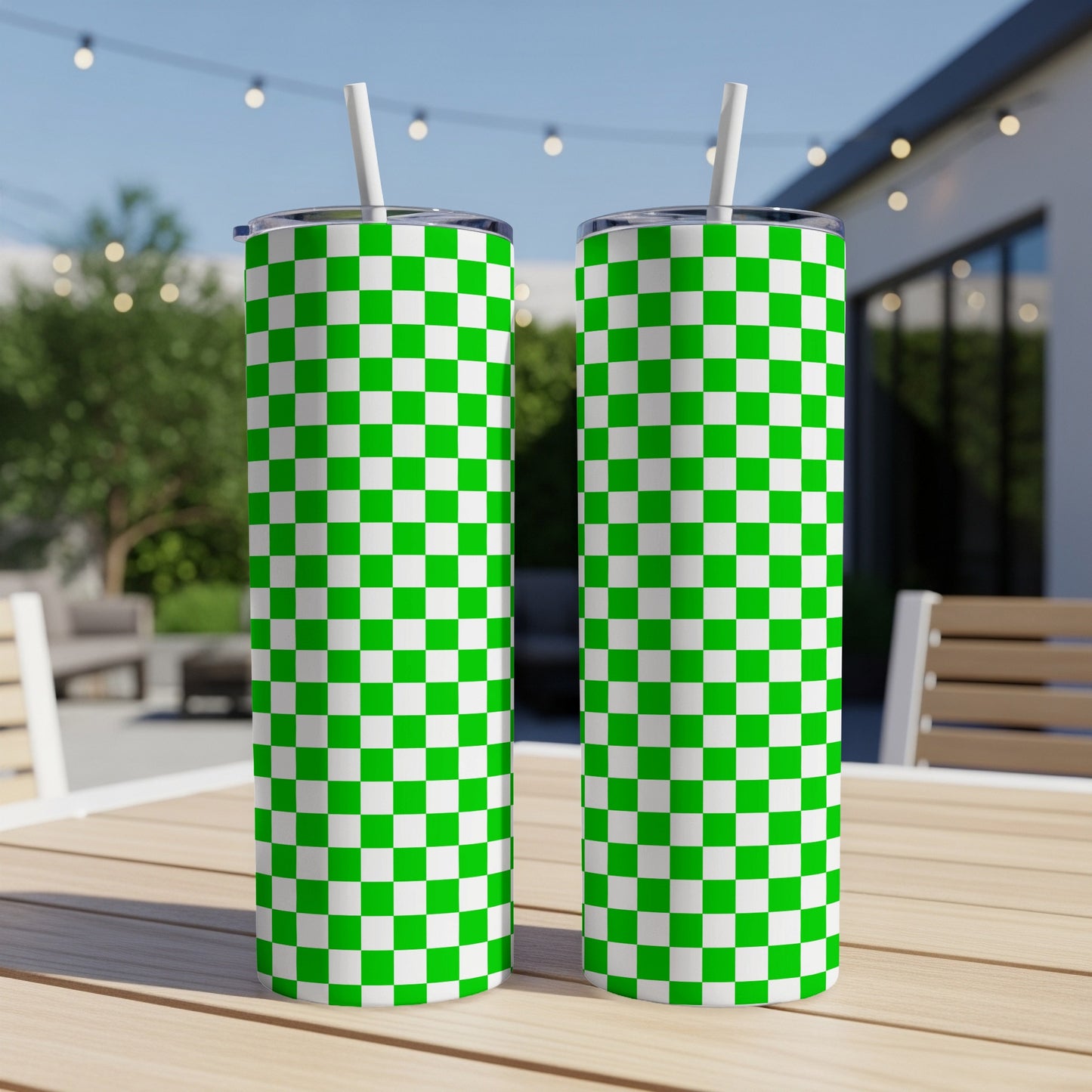 Two green and white checkered tumblers with straws on a table.