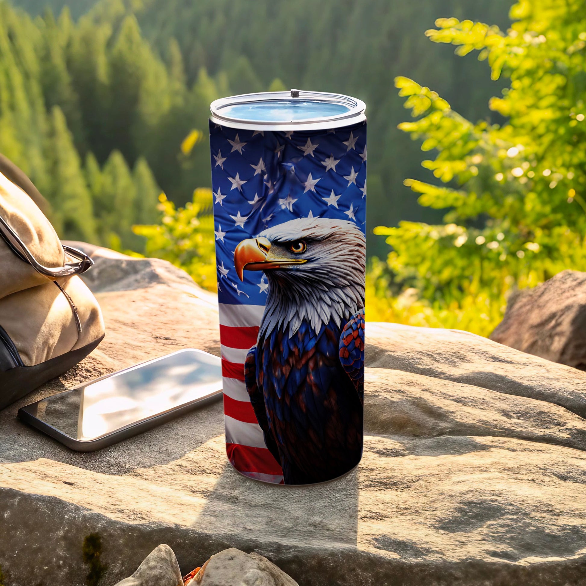 Tumbler with American flag and eagle design, outdoors with phone and bag.