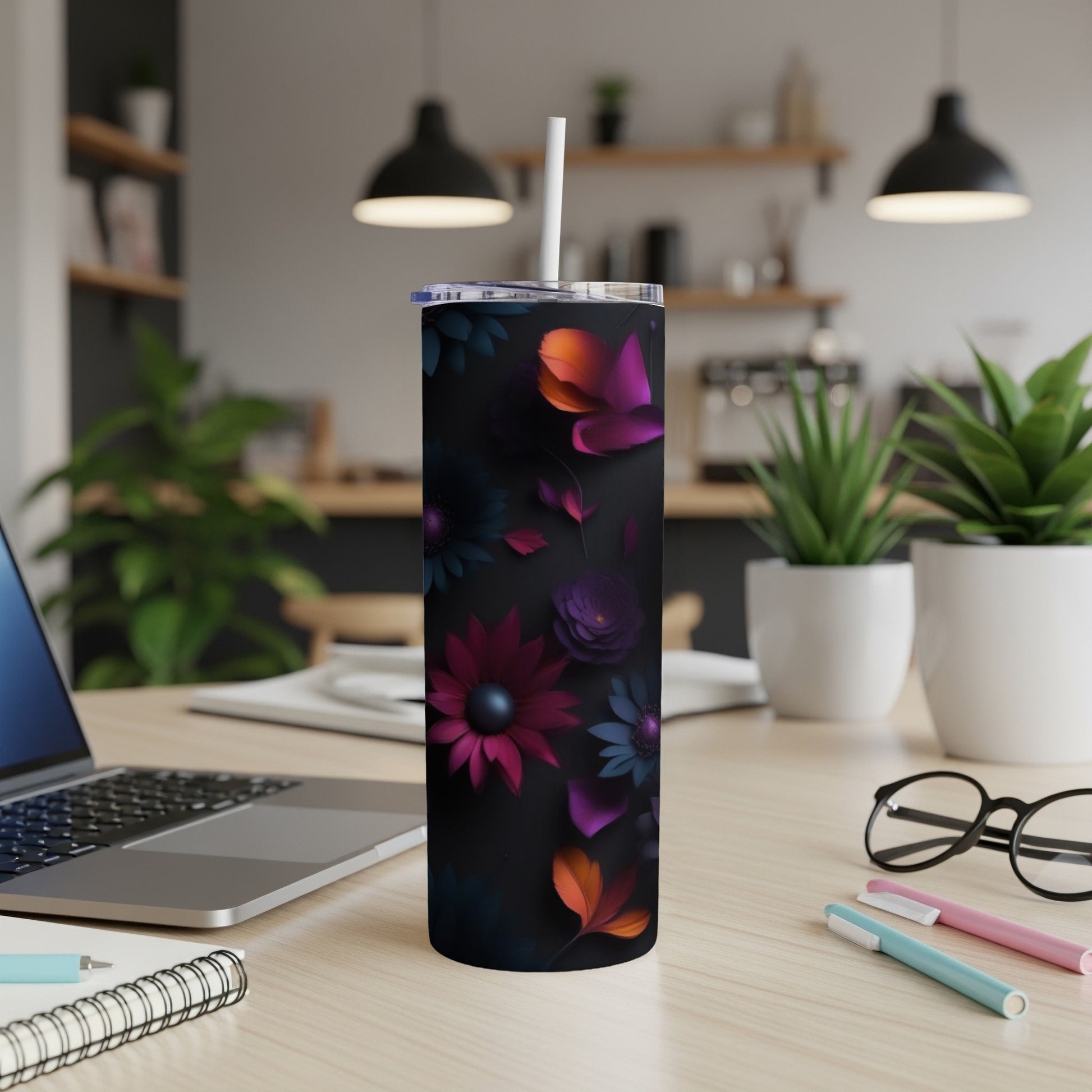 Black tumbler with colorful floral pattern and white straw, on a desk.