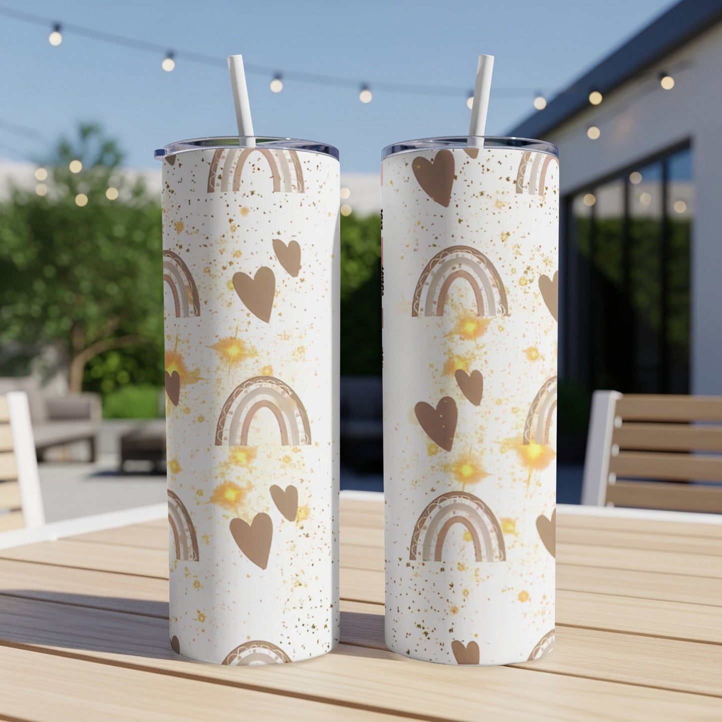 Two white tumblers with a rainbow and heart pattern sit on a wooden table.
