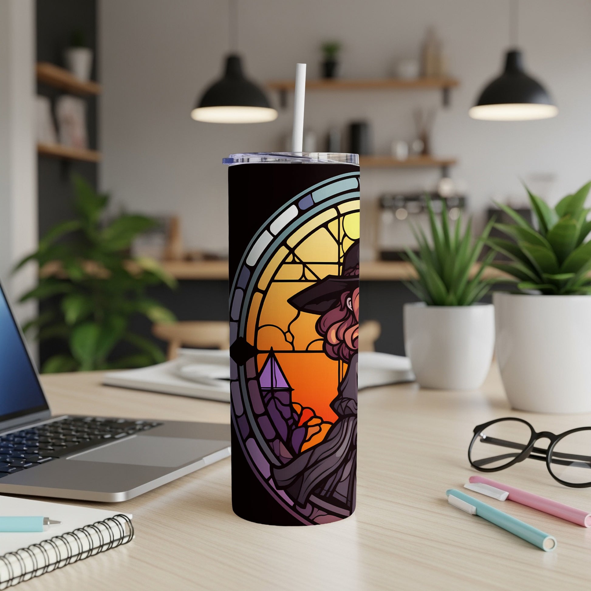 Witch design on a black tumbler with a straw on a desk.
