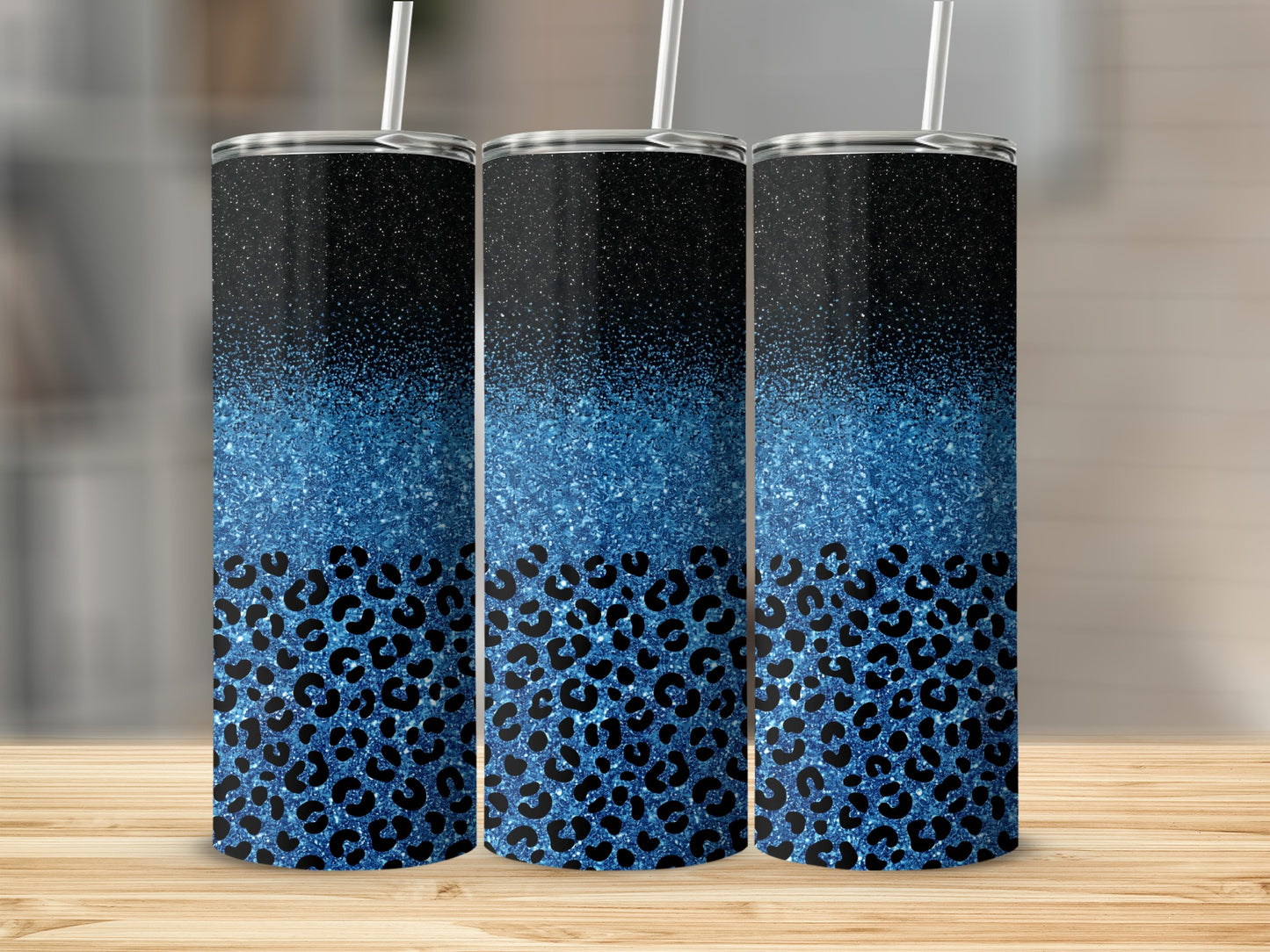 Three blue glitter leopard print tumblers with straws, arranged on a wooden surface.