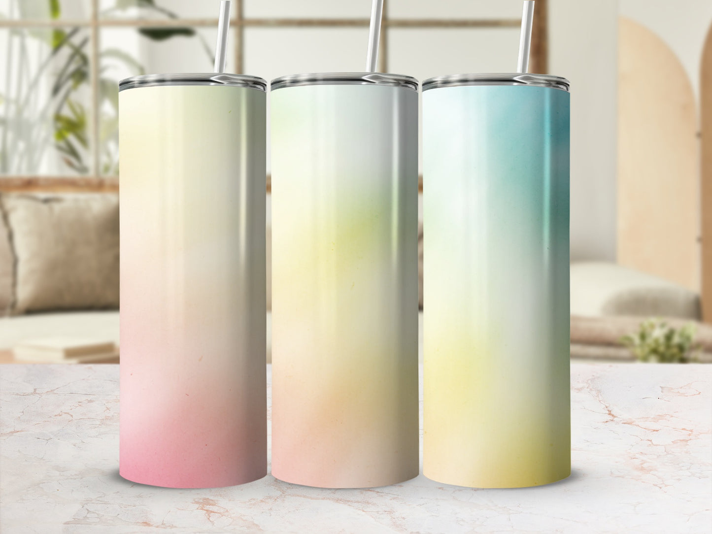 Three gradient tumblers with straws sit on a marble surface.