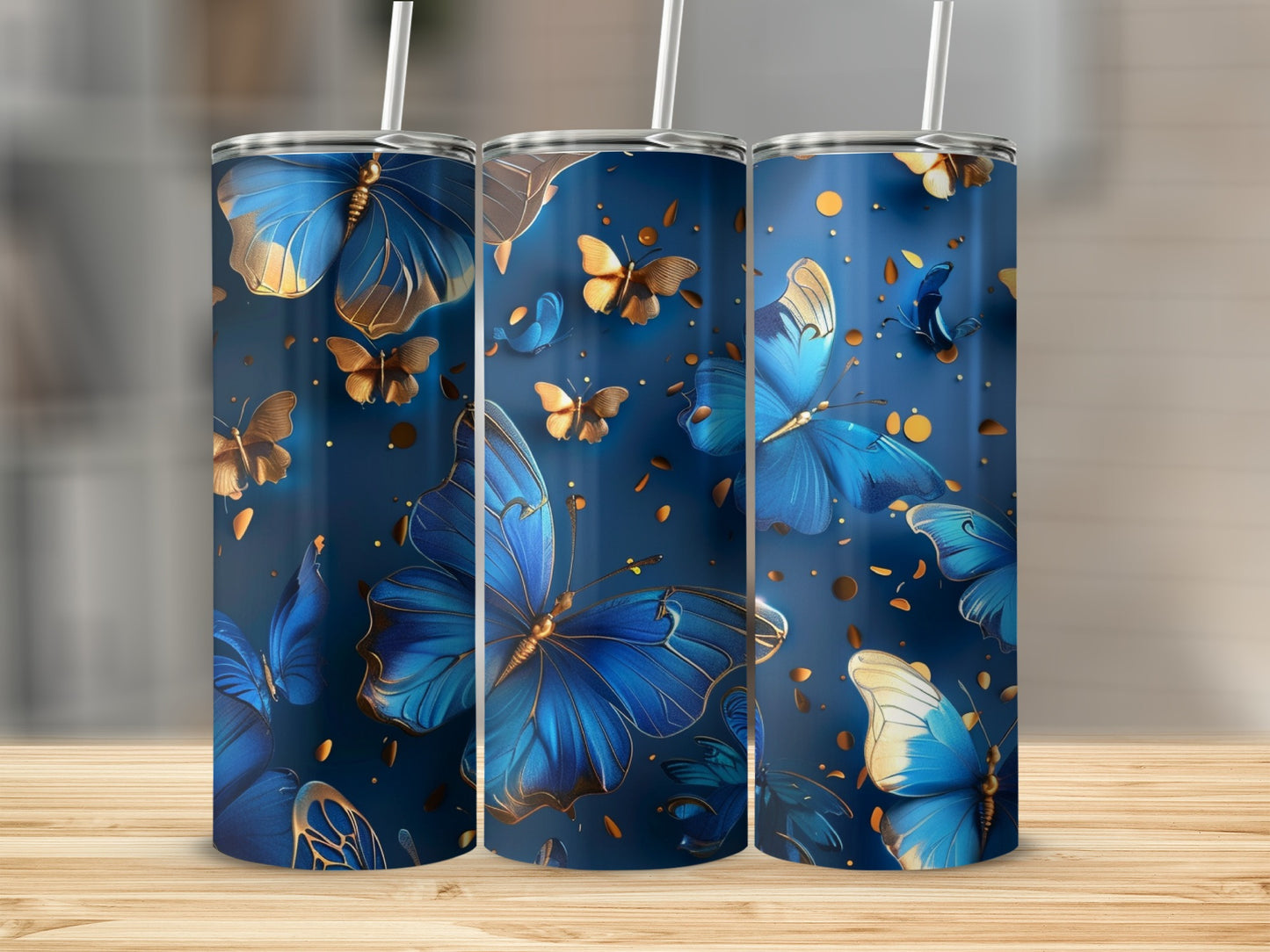 Three blue tumblers with gold and blue butterfly pattern on dark blue background.