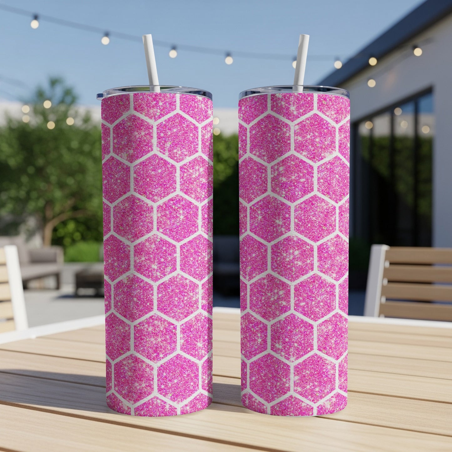 Two pink glitter hexagonal tumblers with white straws on a wooden table.