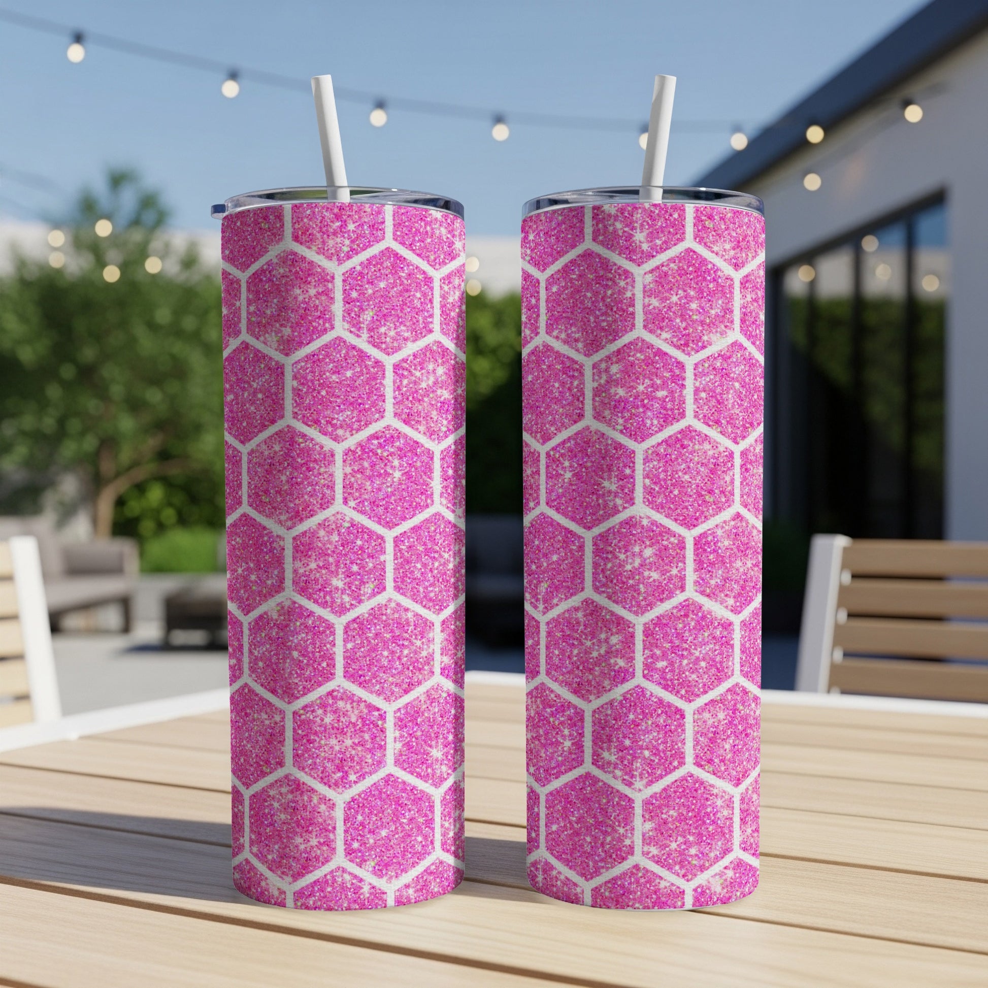 Two pink glitter hexagonal tumblers with white straws on a wooden table.