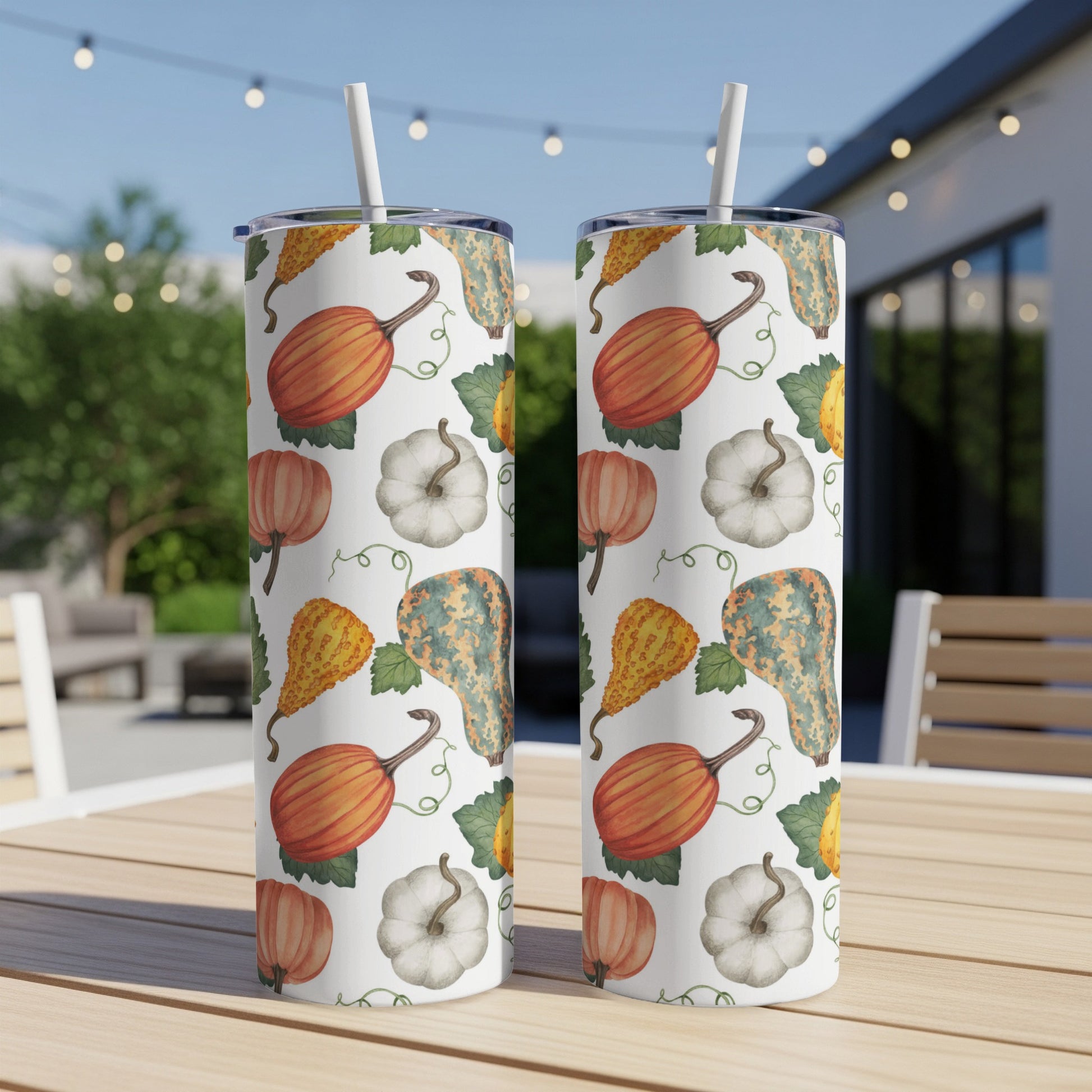 Two tumblers with a fall pumpkin and gourd pattern on a wooden table.