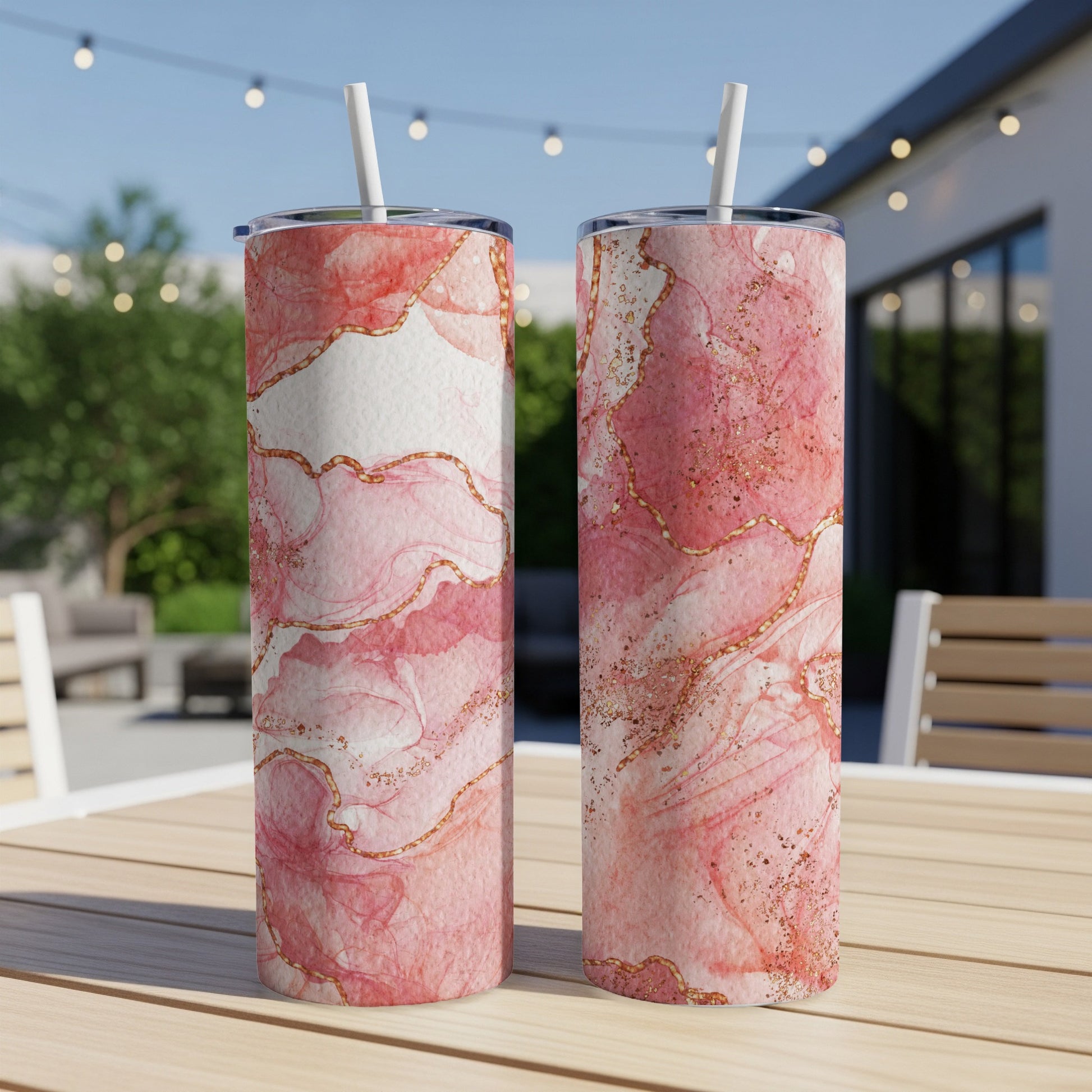 Two pink marble tumblers with gold accents on a wooden table.